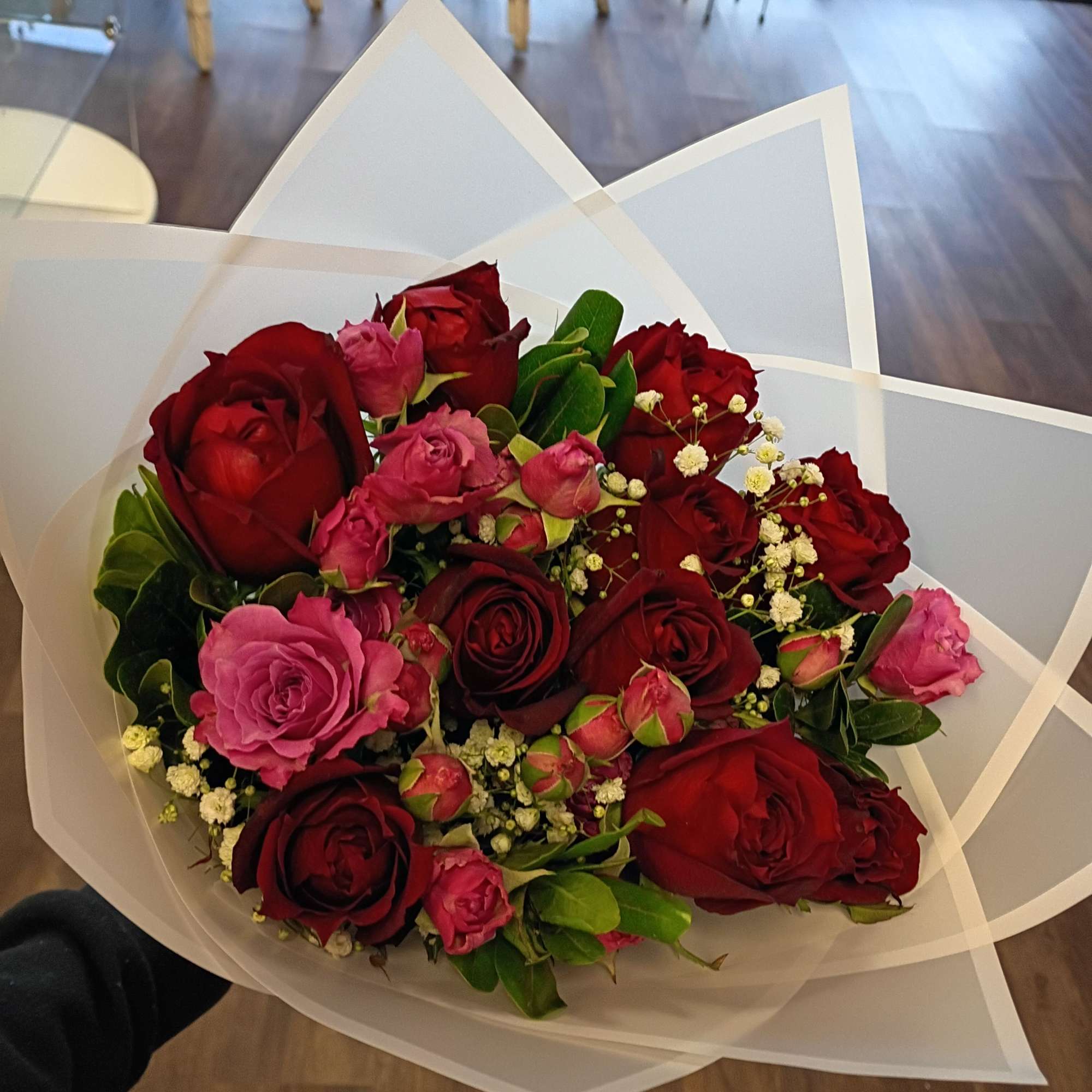 Bouquet of red and pink roses wrapped in white paper