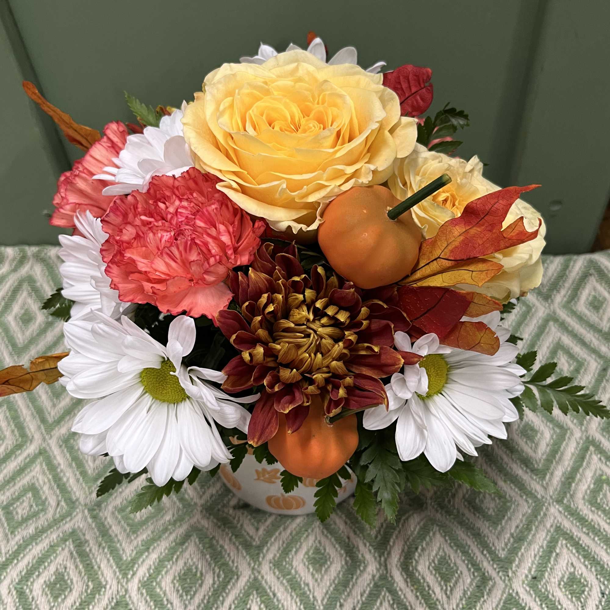 Mixed bouquet with yellow rose, daisies, and autumn accents in a pumpkin vase