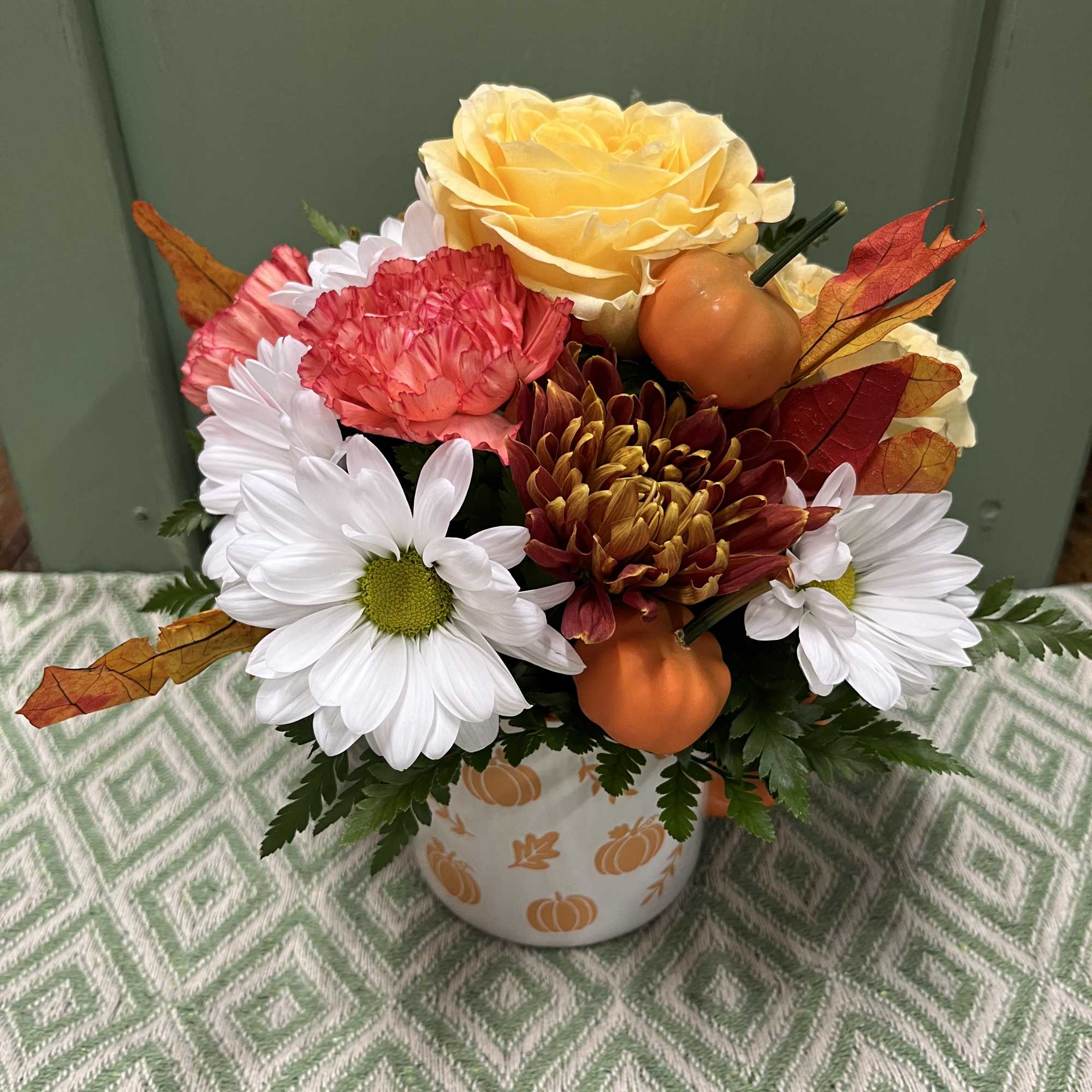 Fall bouquet with roses, daisies, and pumpkins in a pumpkin-patterned vase