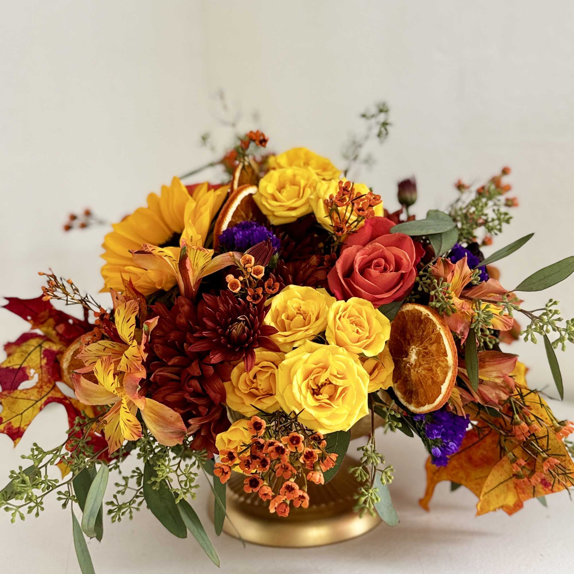 Autumn bouquet with yellow and red roses in a gold vase