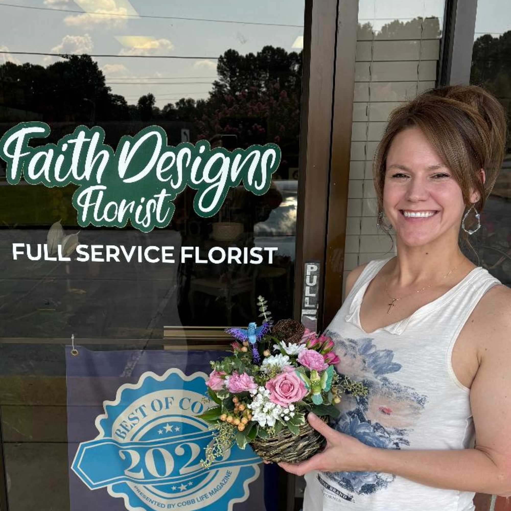 Woman holding a small mixed flower basket outside a florist shop