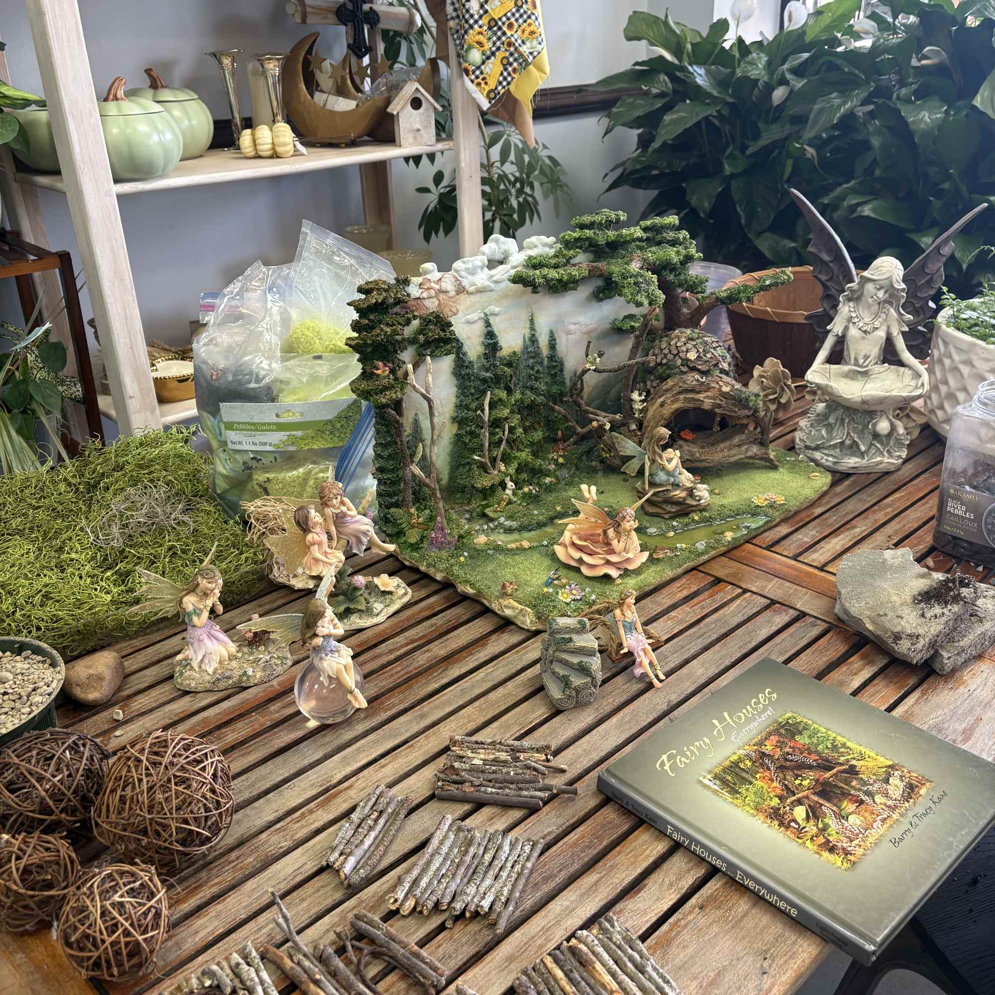 Fairy garden display with miniature figurines, moss, and a small woodland scene