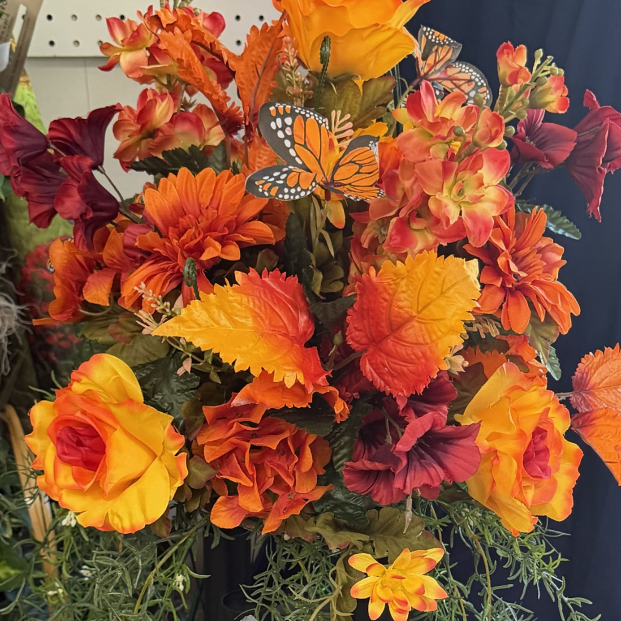 Autumn floral arrangement with orange and yellow flowers and butterfly accents