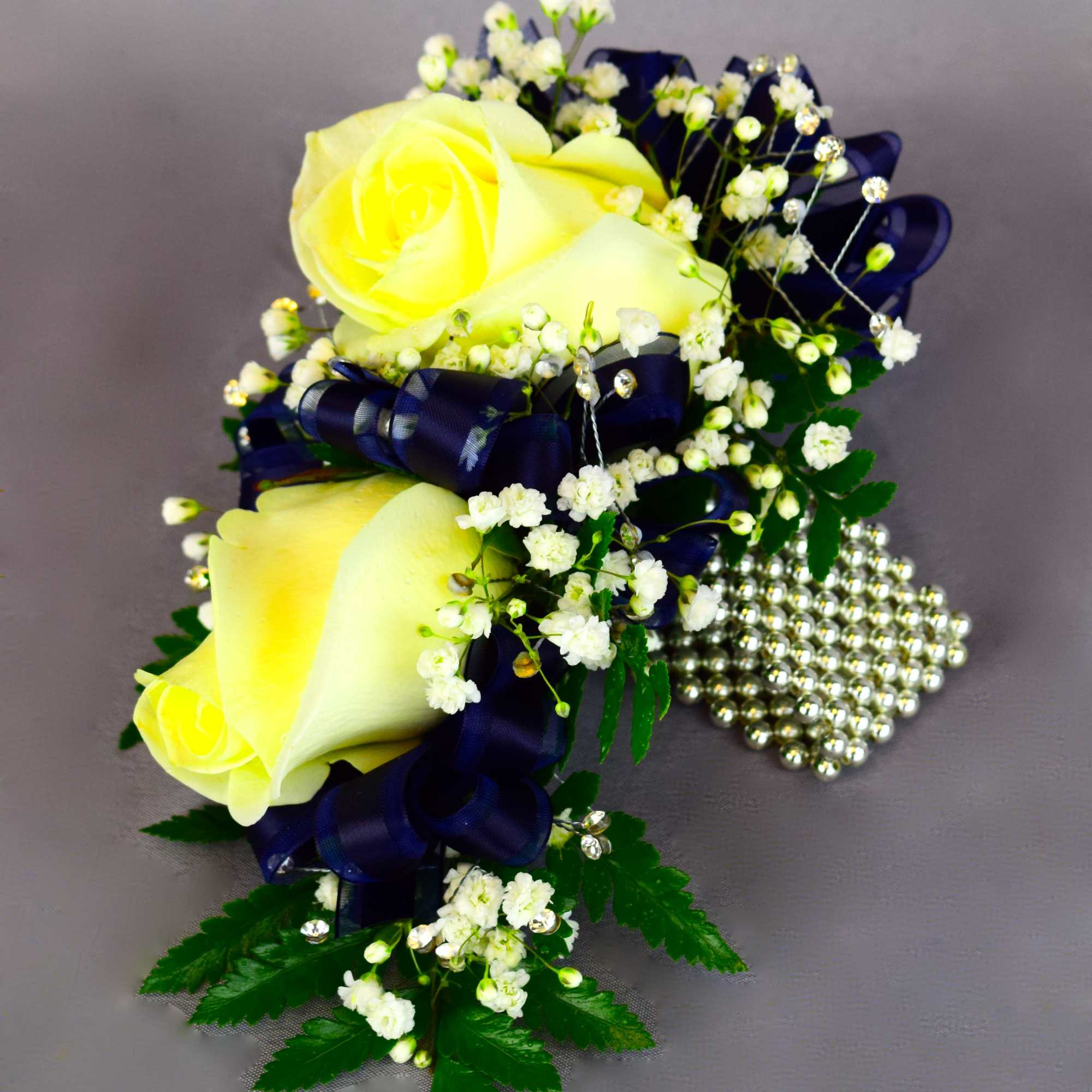 Yellow rose corsage with white baby's breath and navy ribbon