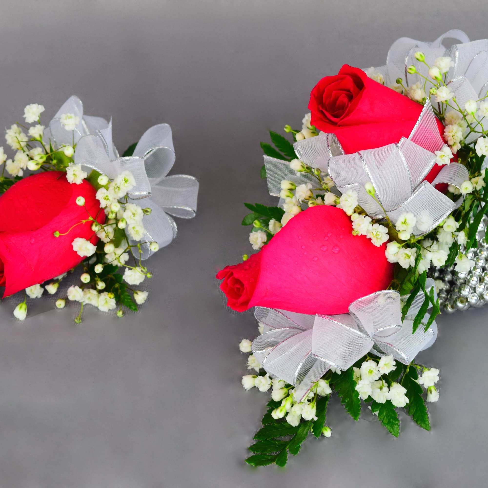 Pink rose corsages with white baby's breath and silver ribbon bows