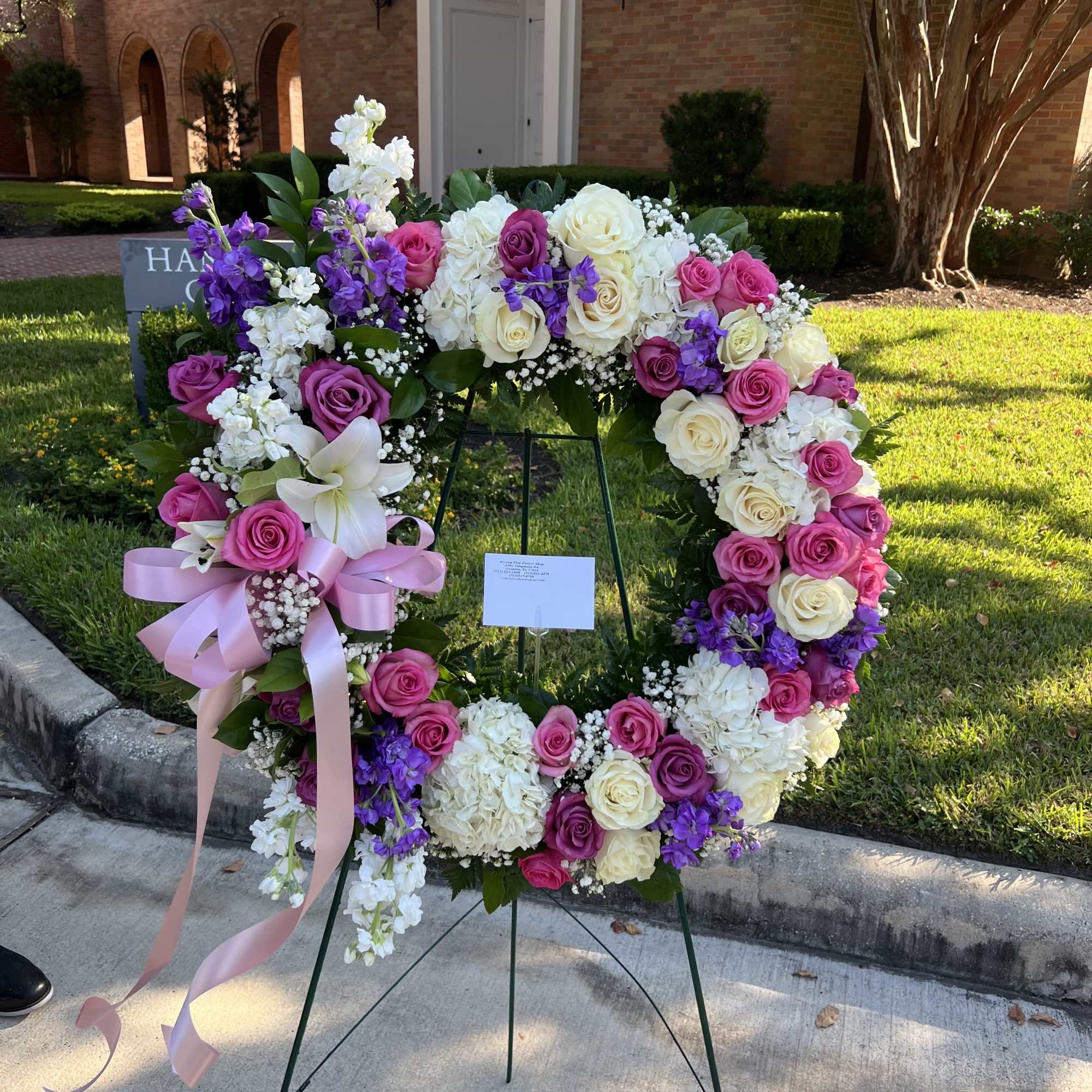 Large floral wreath on an easel with pink, white, and purple flowers