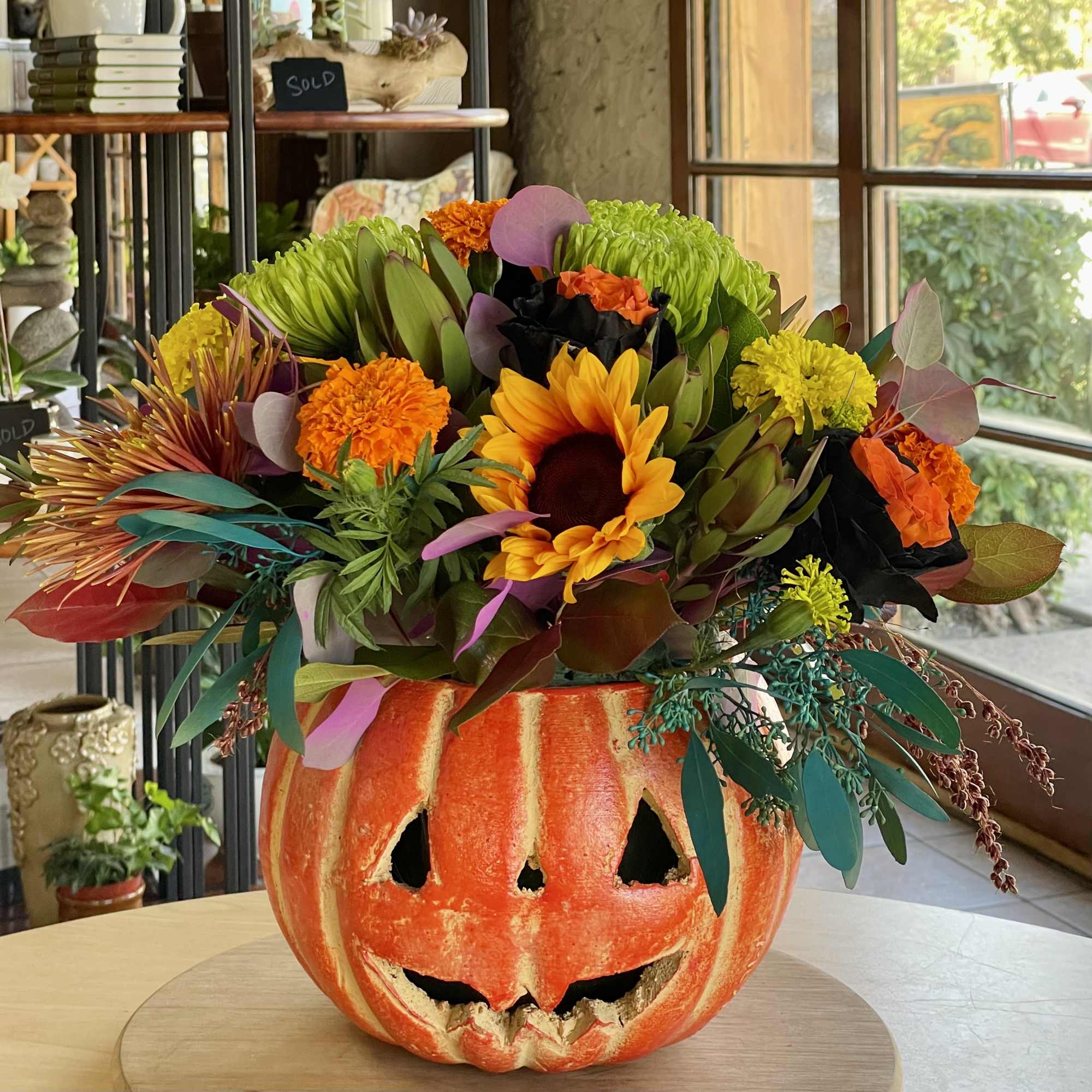 Floral arrangement in a carved pumpkin container with sunflowers and mums