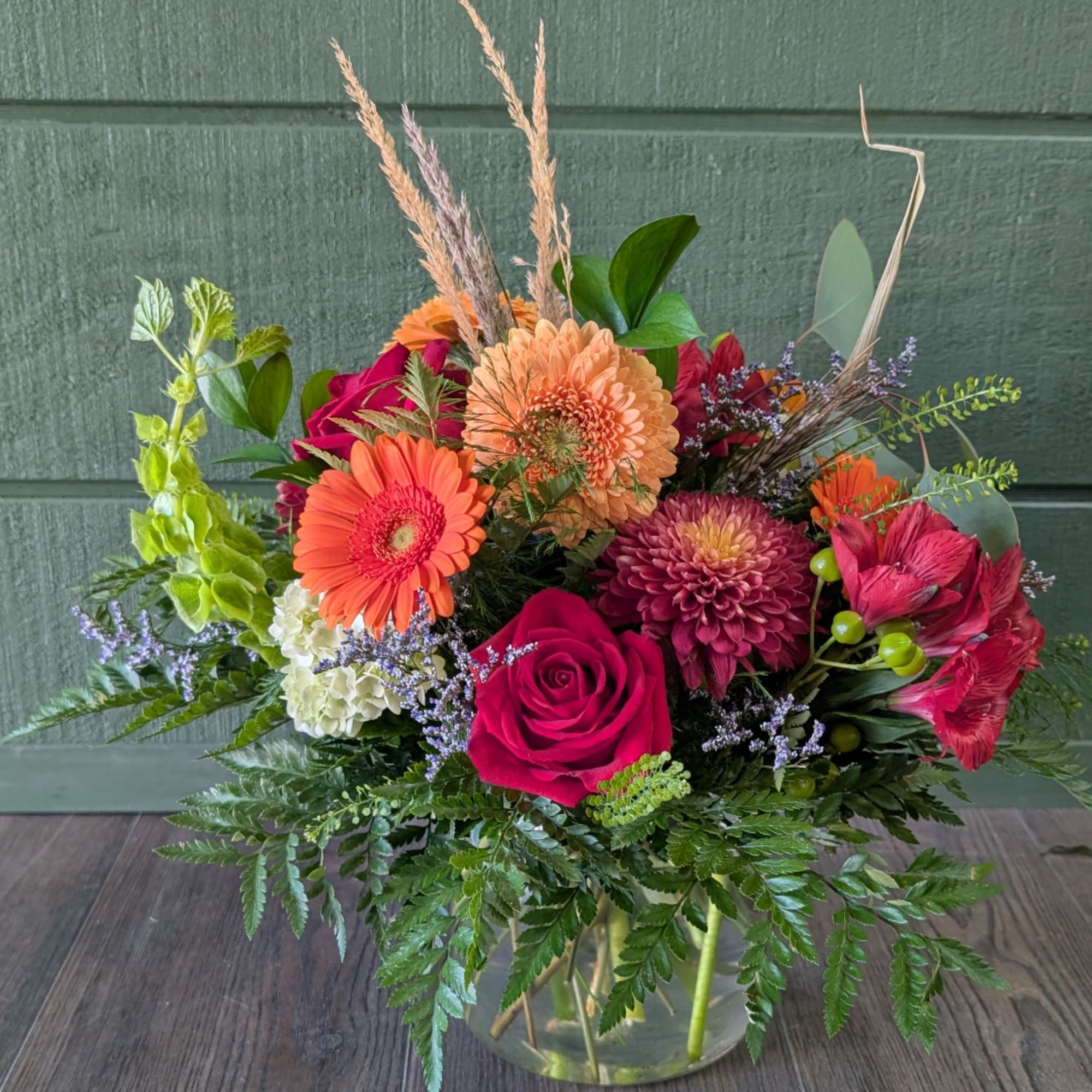 Mixed bouquet in a clear glass vase with roses, gerbera daisies, and chrysanthemums