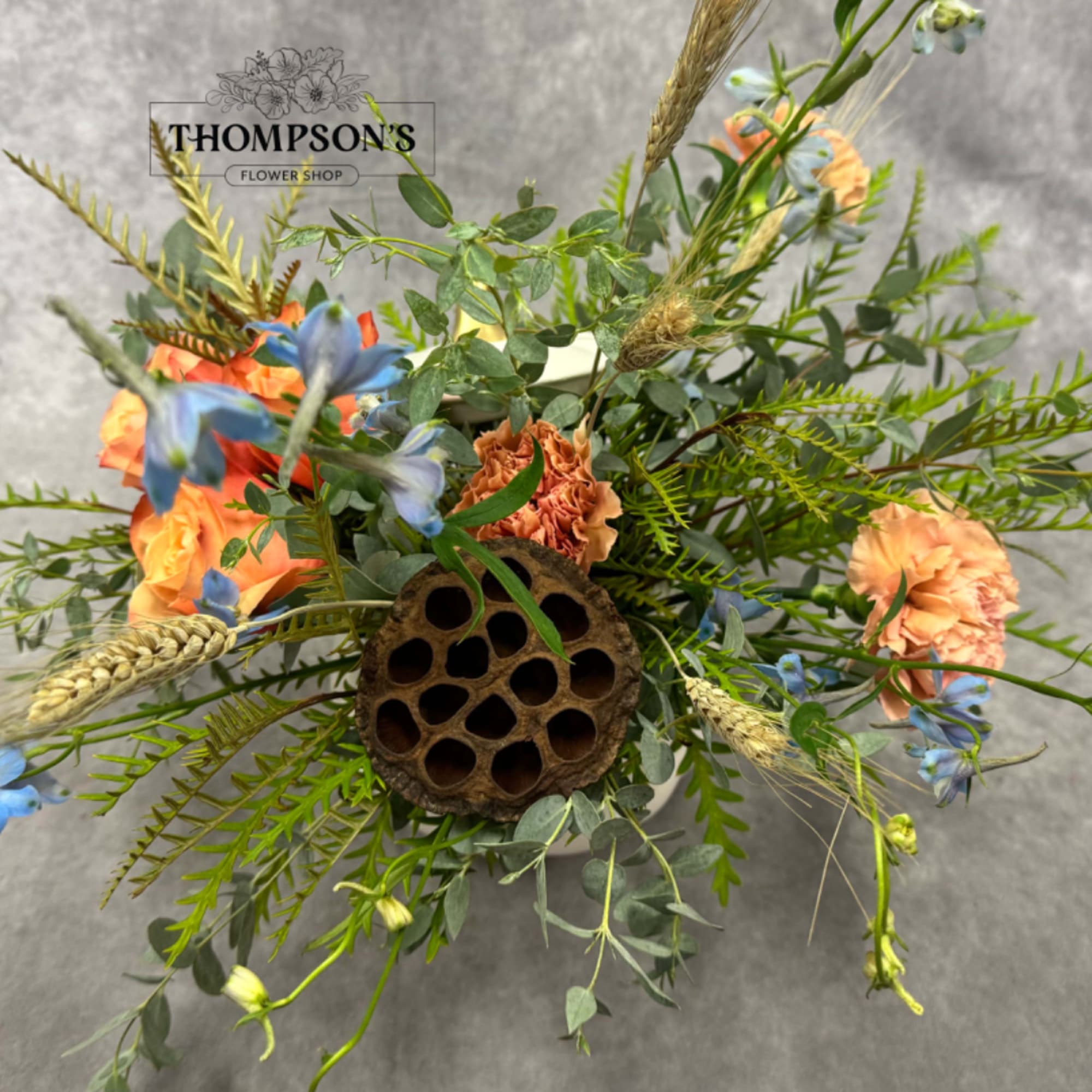 Mixed floral arrangement with orange and blue flowers in a vase