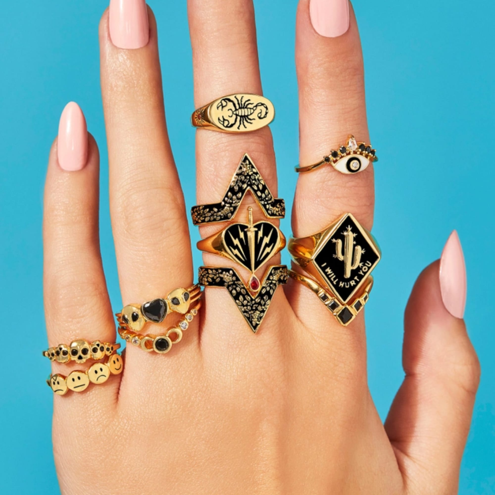 Hand wearing multiple gold rings with black and white designs