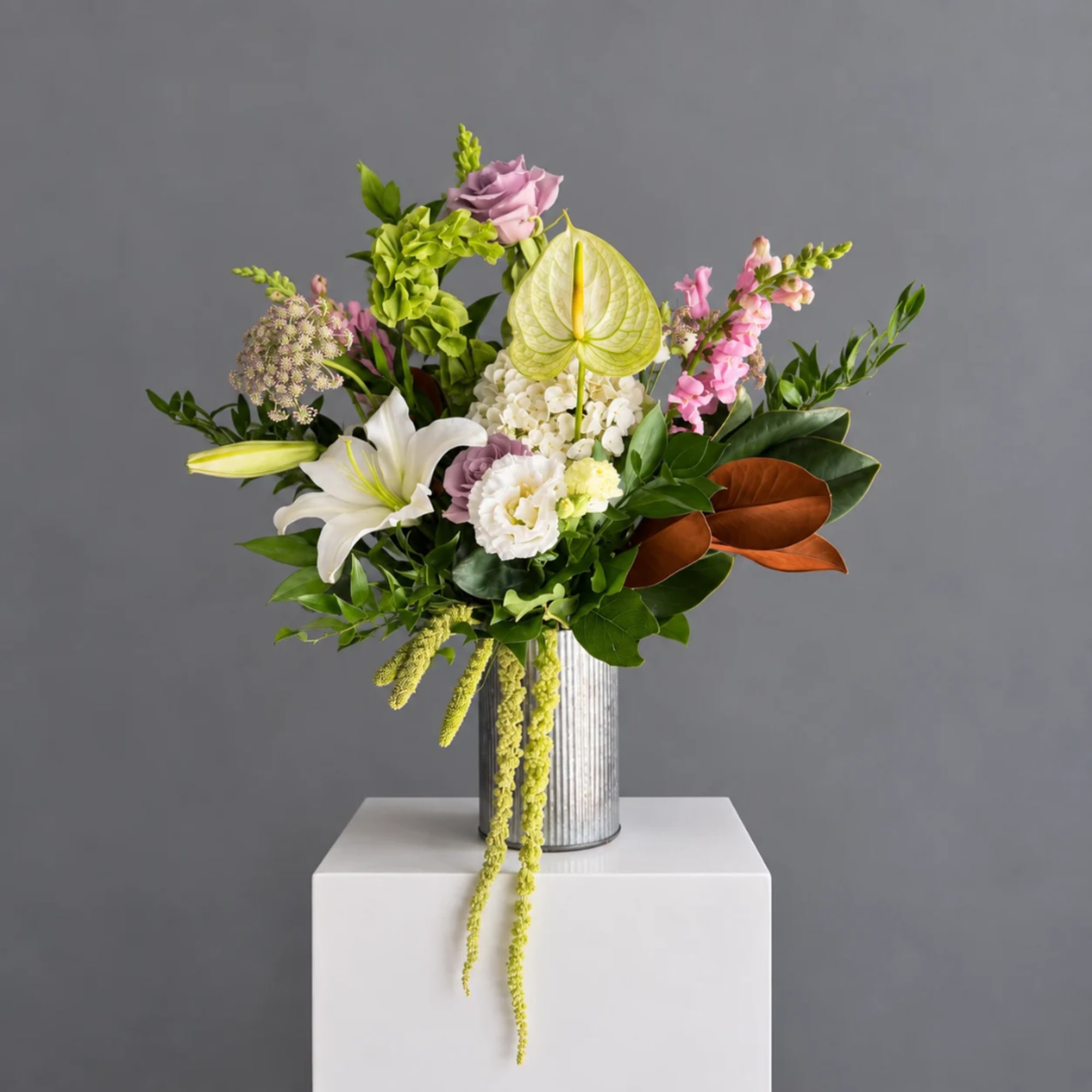 Mixed floral arrangement in a ribbed metal vase with white lilies and pink blooms