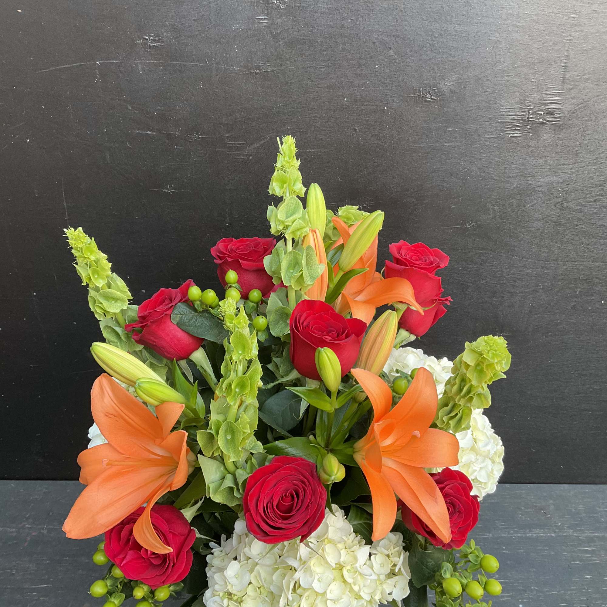 Bouquet of red roses, orange lilies, and white hydrangeas in a vase