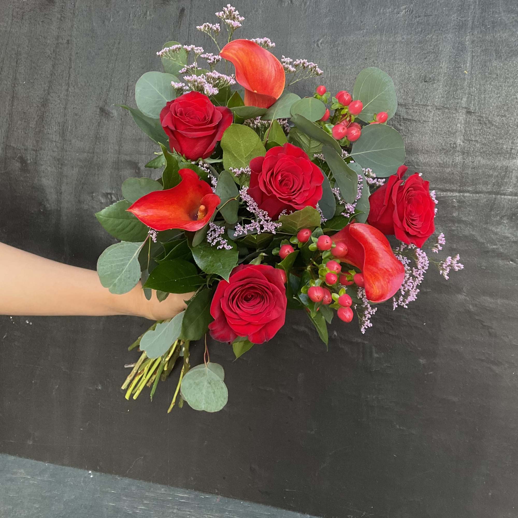 Bouquet of red roses and orange calla lilies with greenery