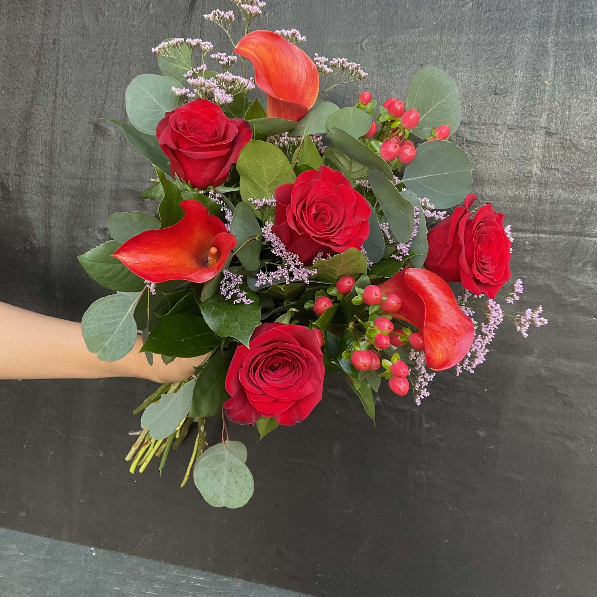 Bouquet of red roses and orange calla lilies with berries