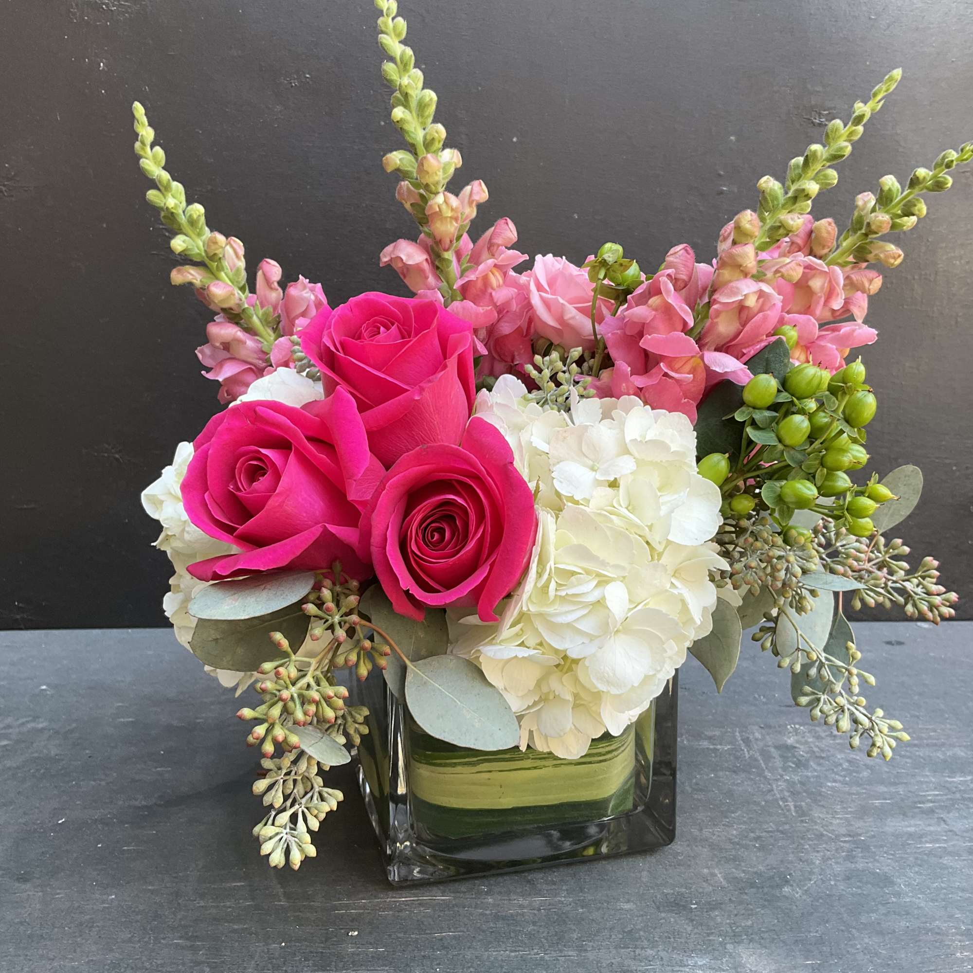Pink roses and white hydrangeas in a square glass vase