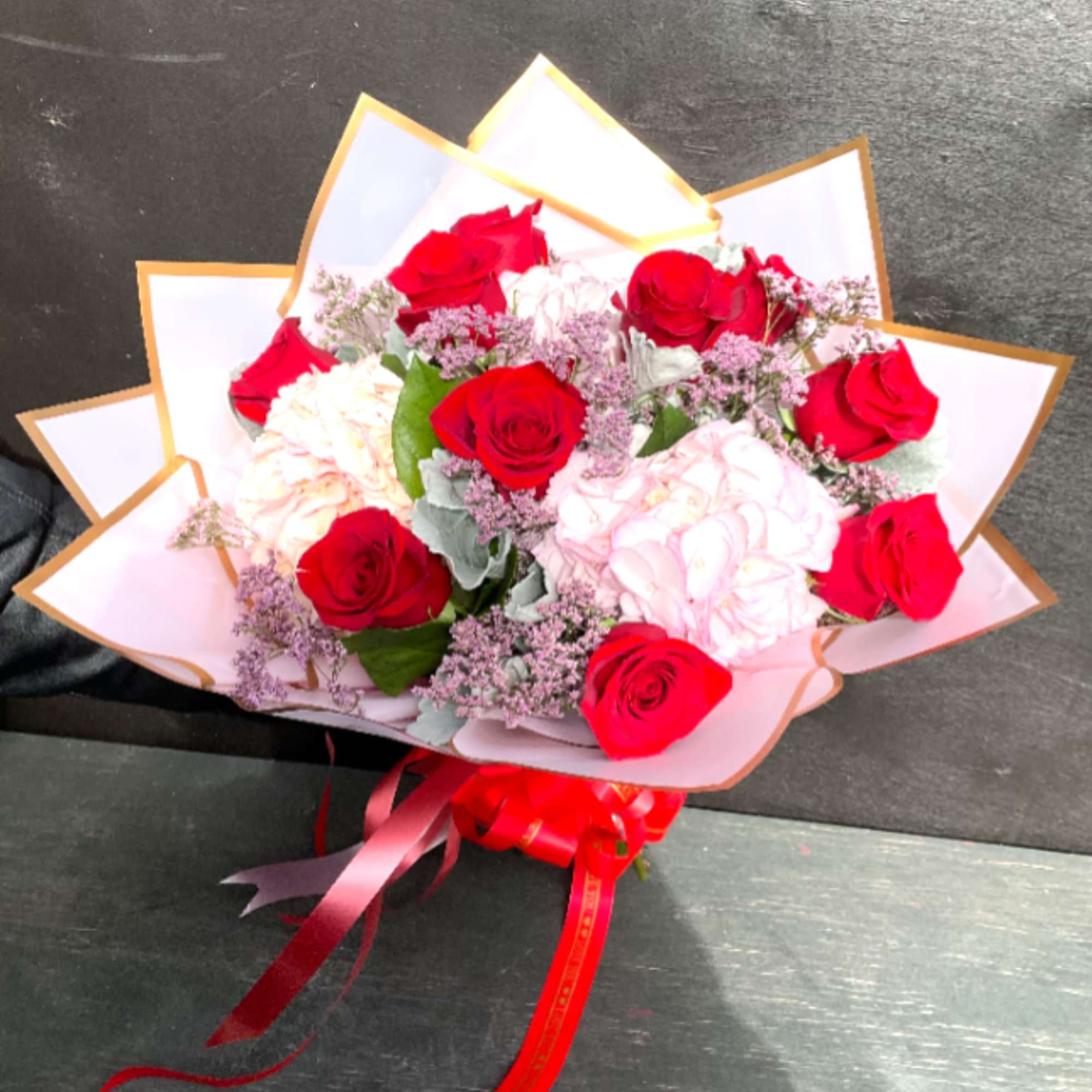 Bouquet of red and pale pink roses wrapped in white paper