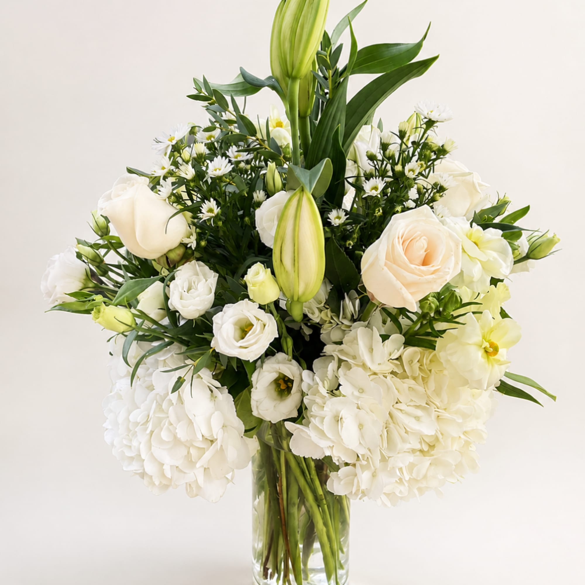 White roses and lilies arranged in a clear glass vase