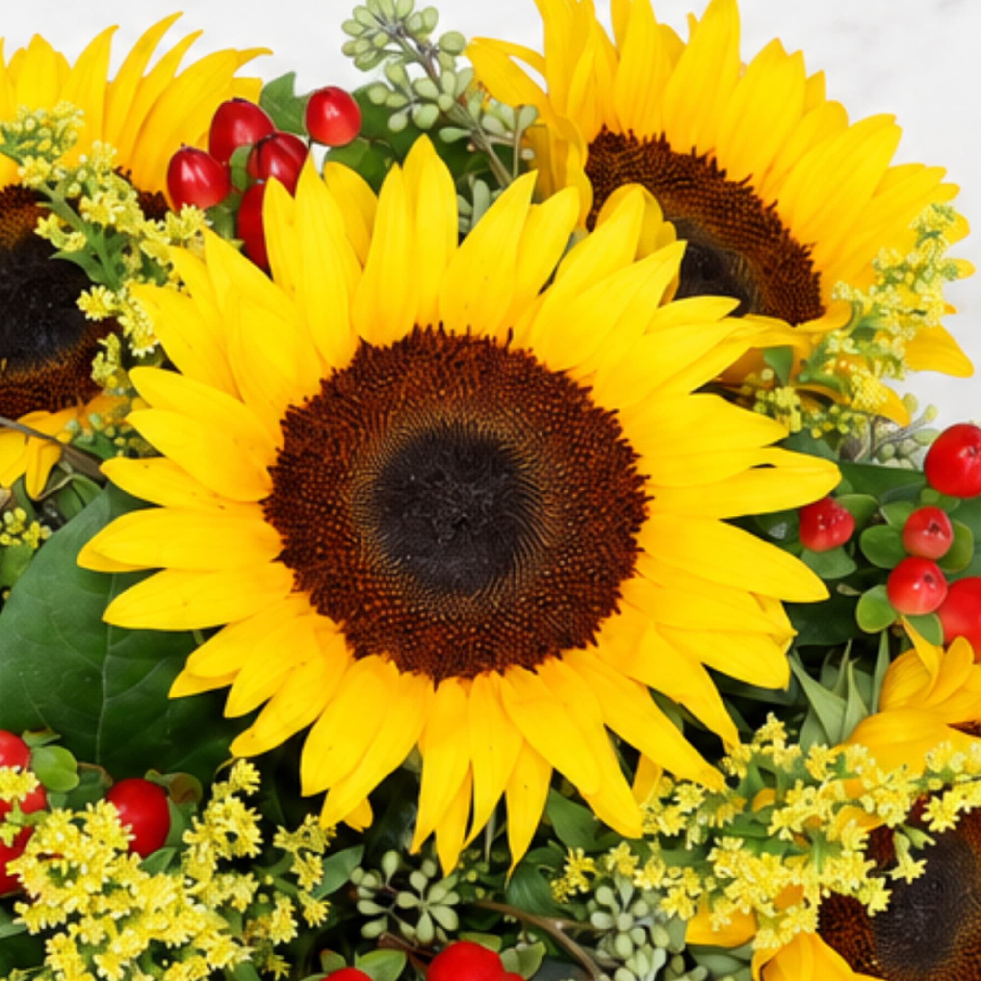 Bouquet of bright yellow sunflowers with red berry accents