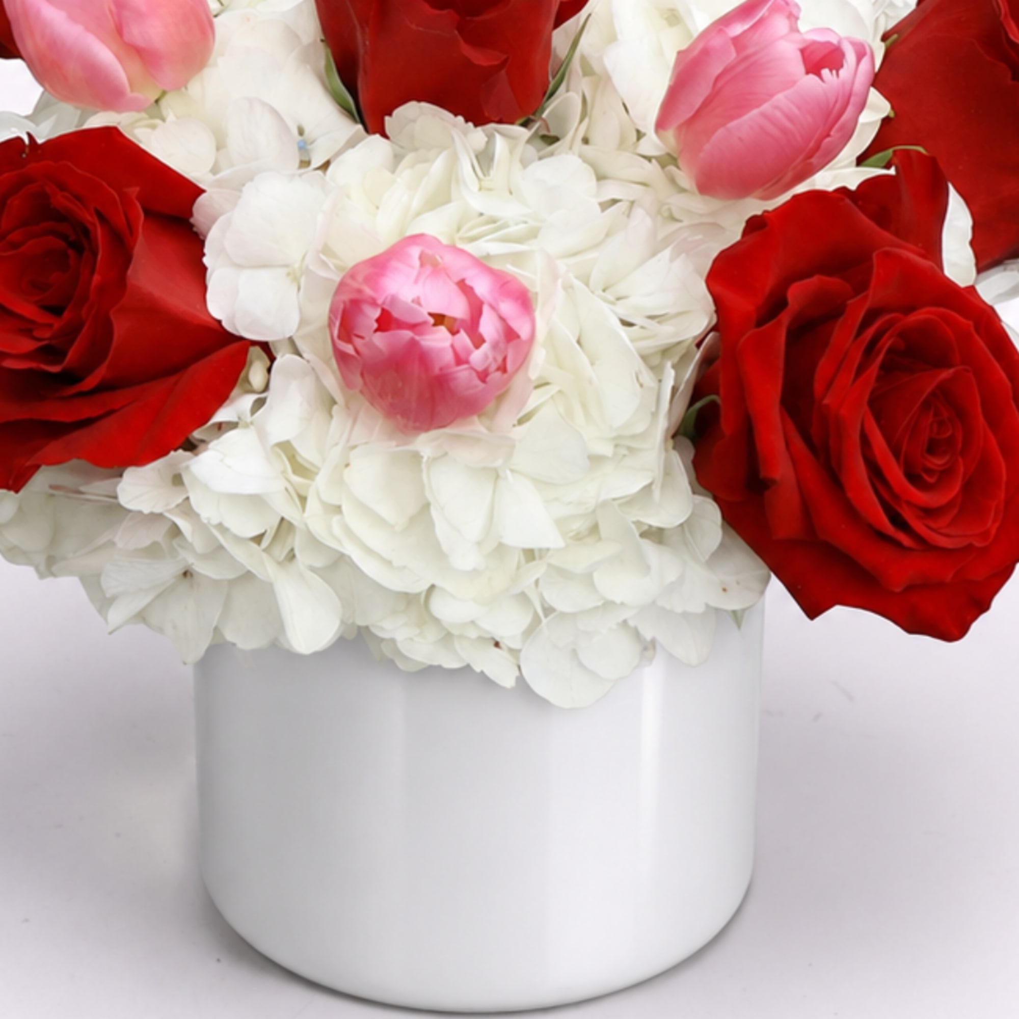 Red roses and pink tulips in a white vase