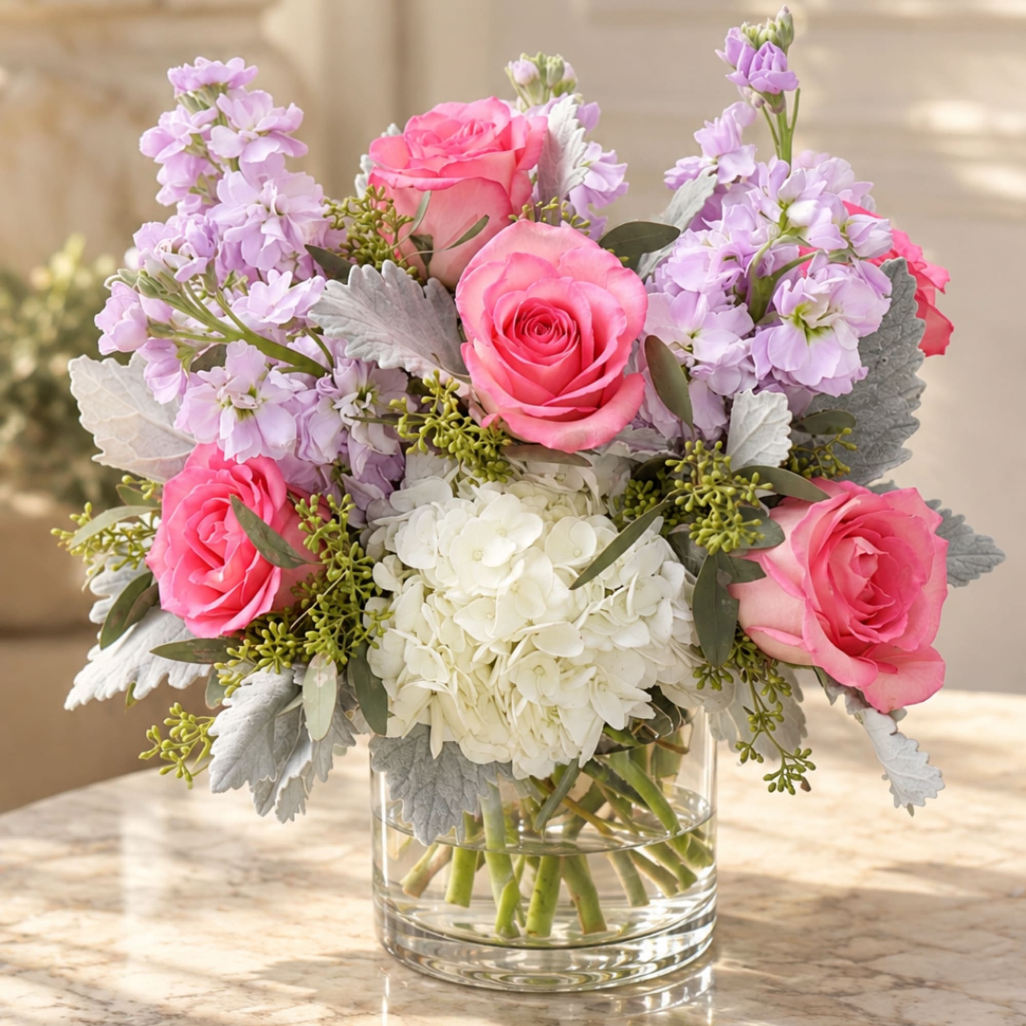 Pink roses and lavender flowers arranged in a clear glass vase