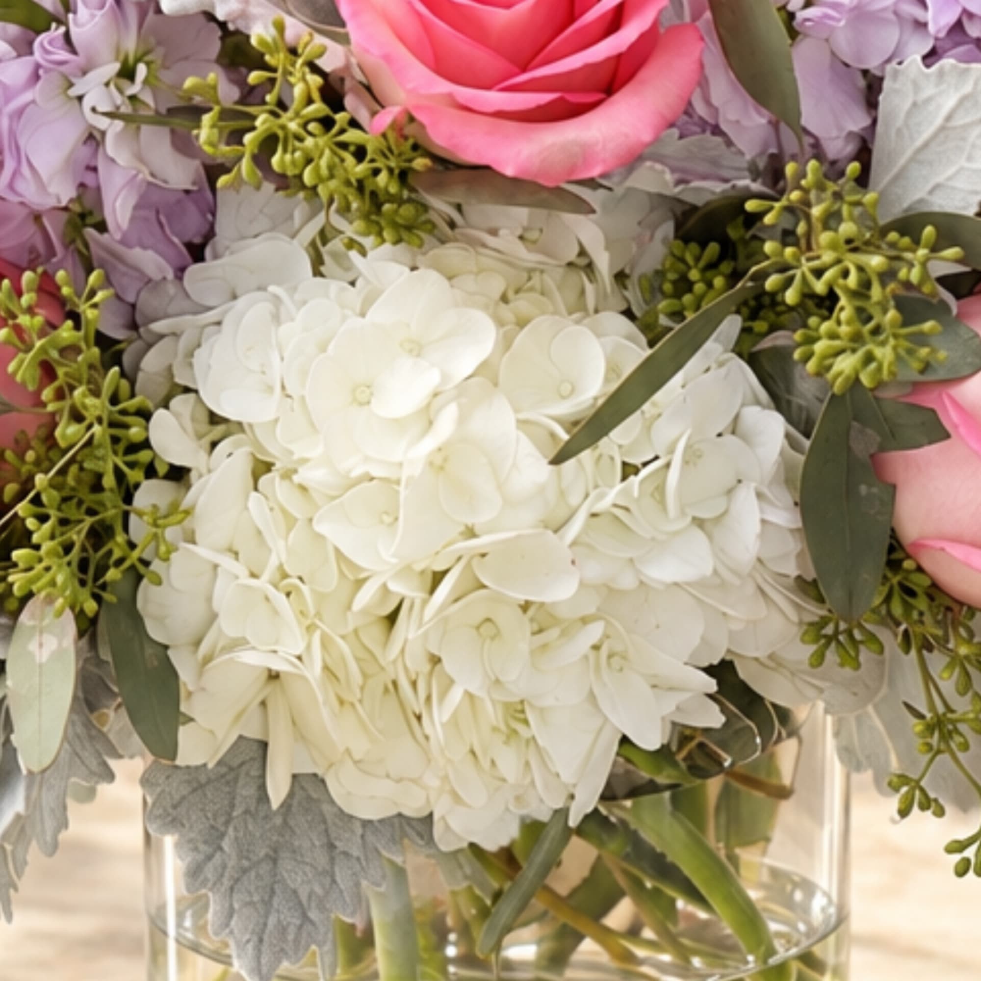 Pink rose and white hydrangea bouquet in a clear glass vase