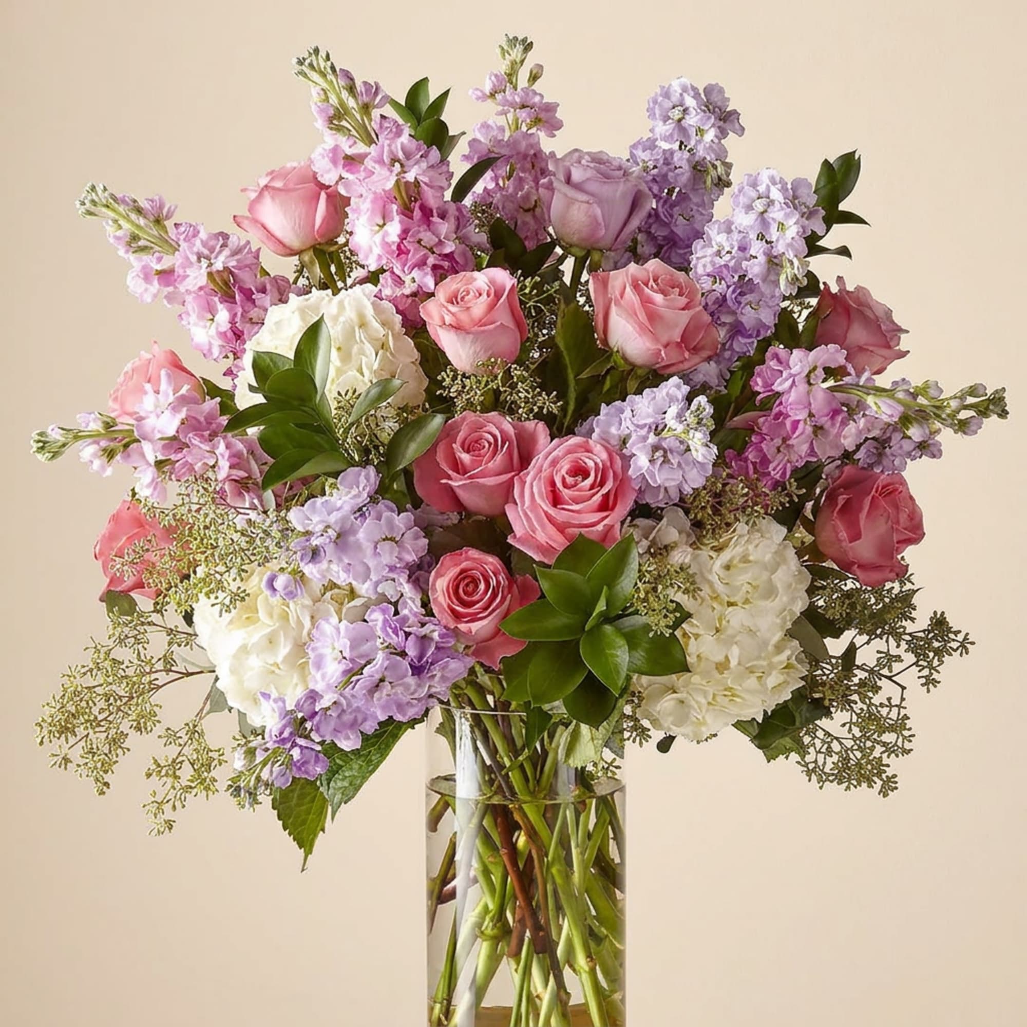 Pink and lavender roses with white hydrangeas in a clear glass vase