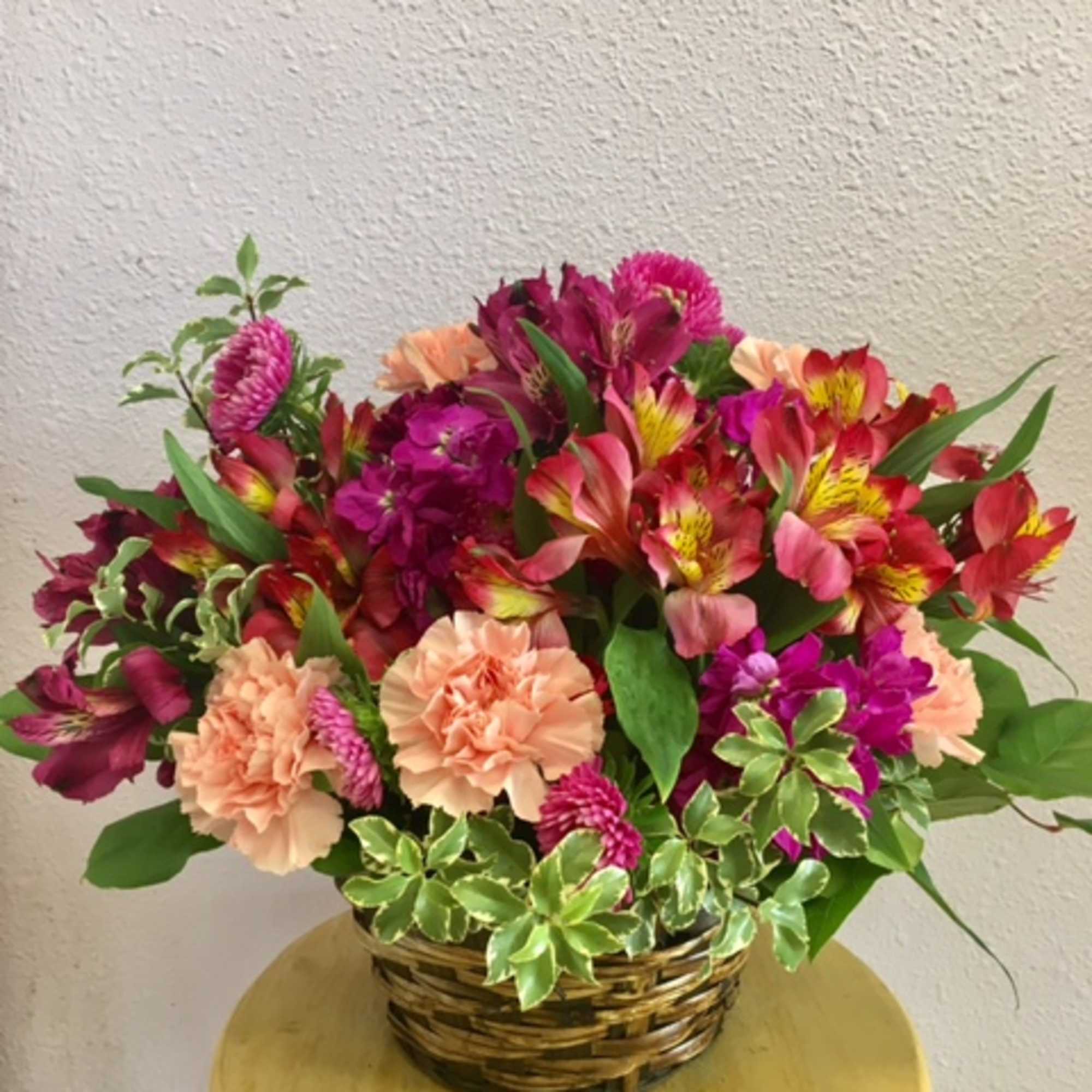 Mixed pink and peach flowers in a woven basket