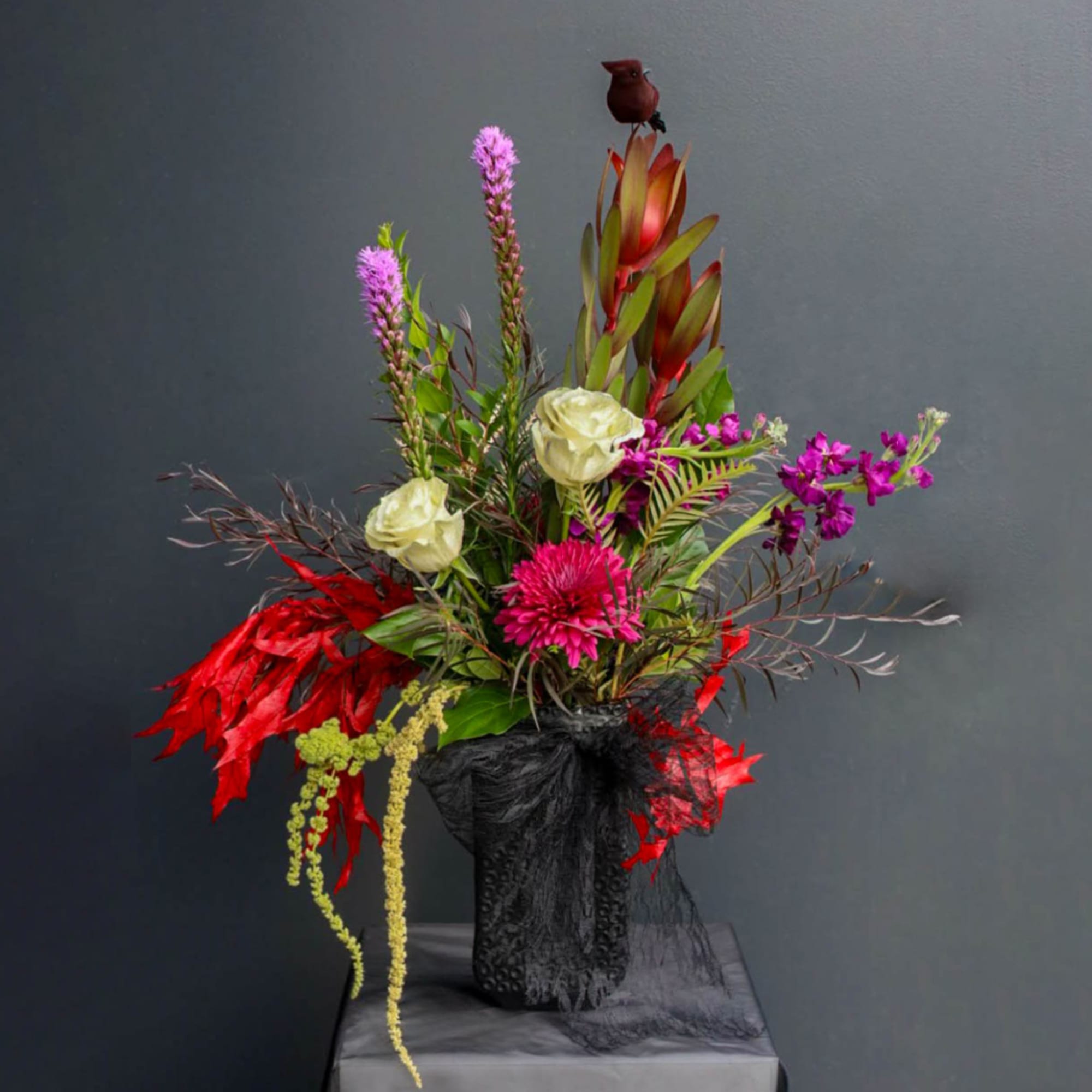 Tall floral arrangement with pink, white, and red blooms in a black vase