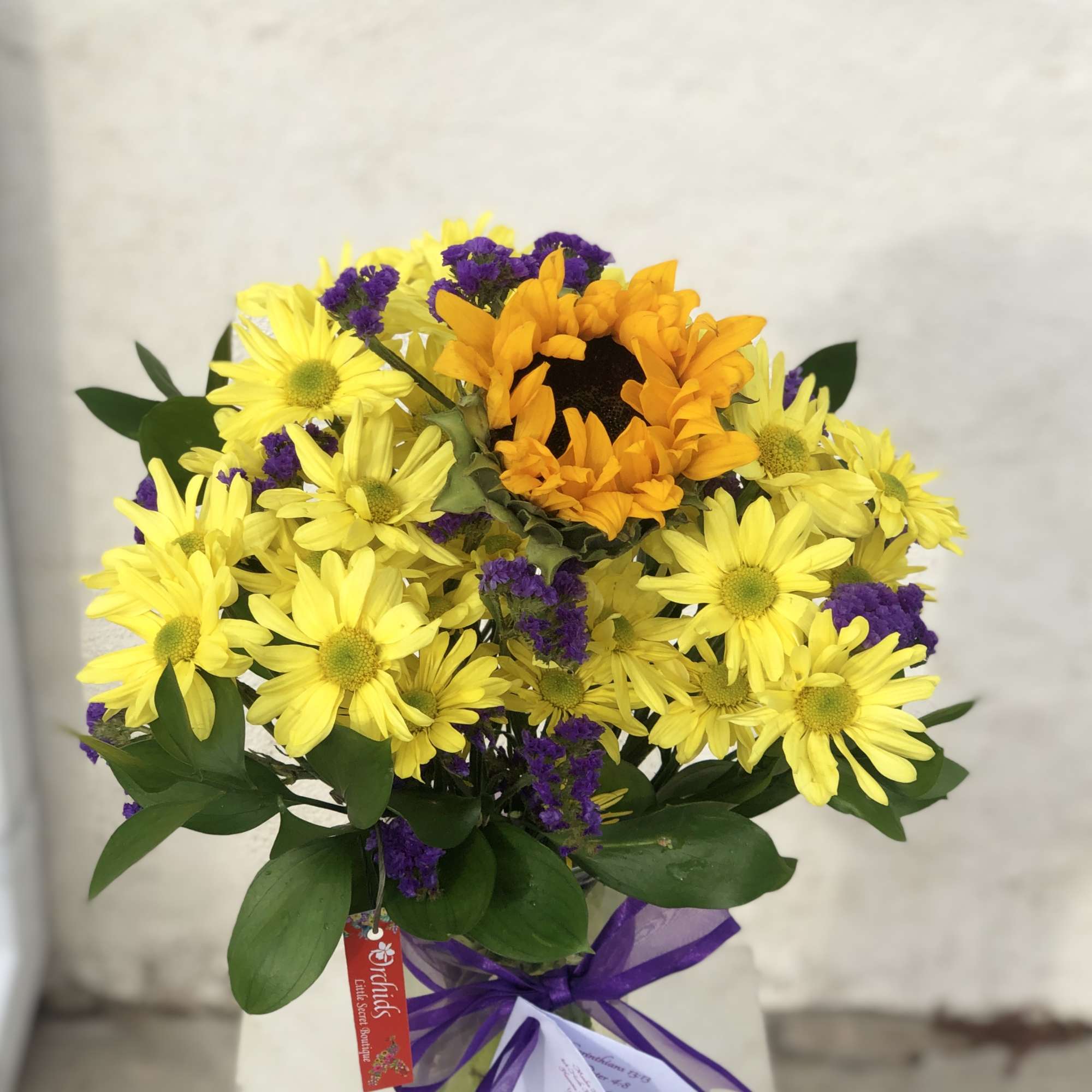 Yellow daisies and an orange sunflower bouquet in a glass vase