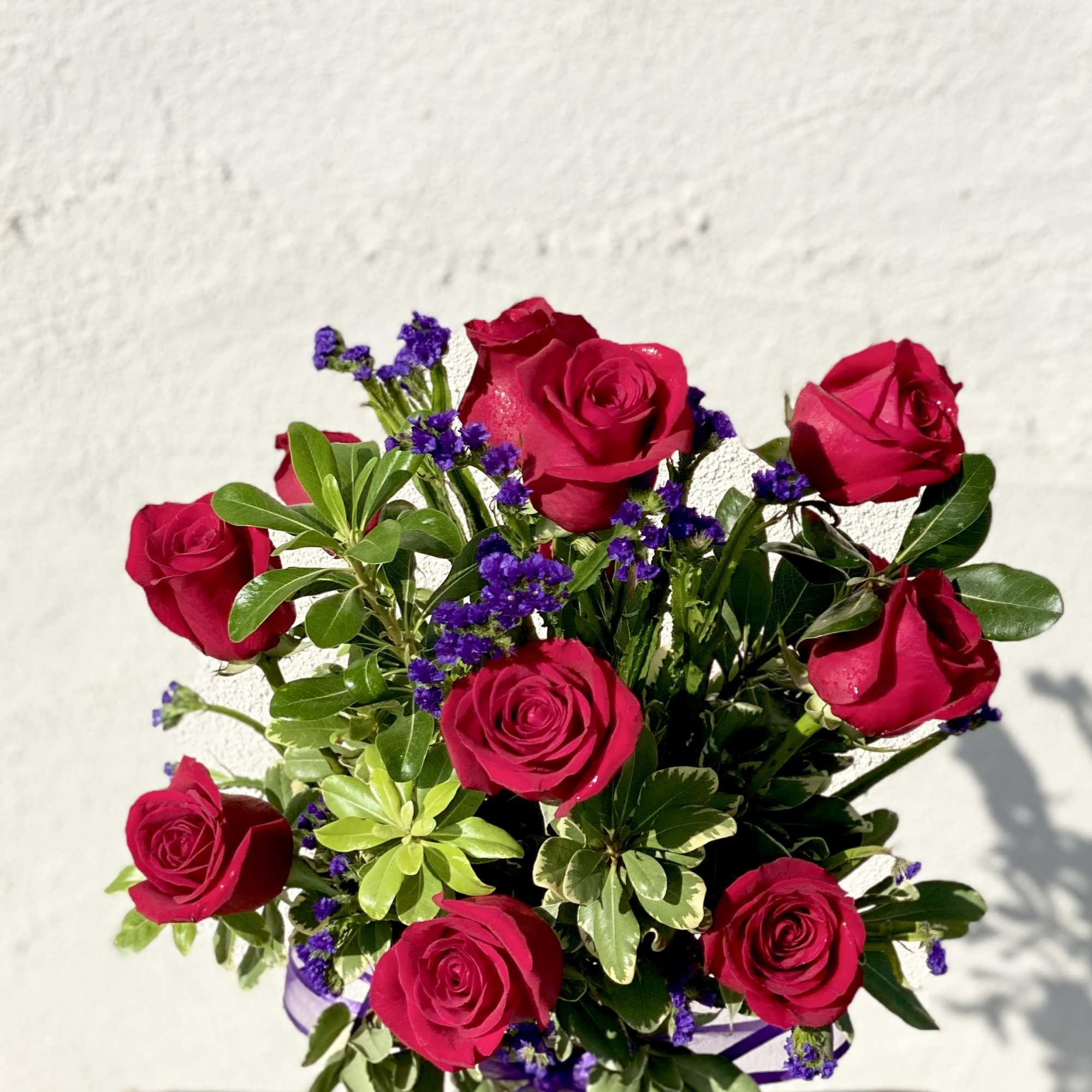 Bouquet of red roses with purple filler in a glass vase