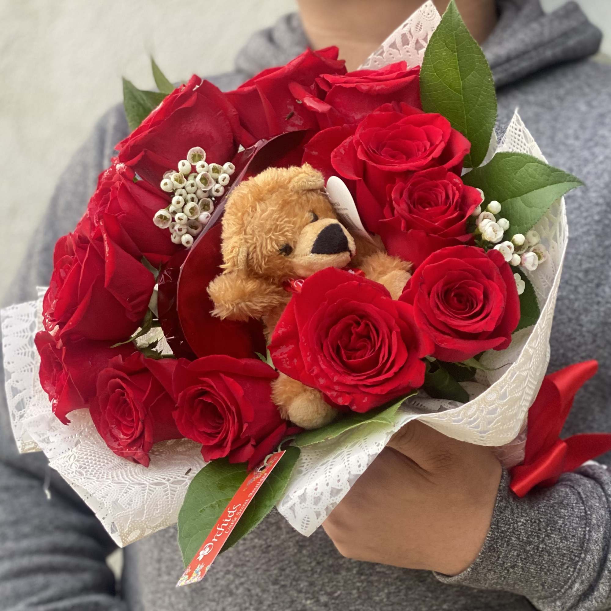 Bouquet of red roses with a small teddy bear in white lace wrap