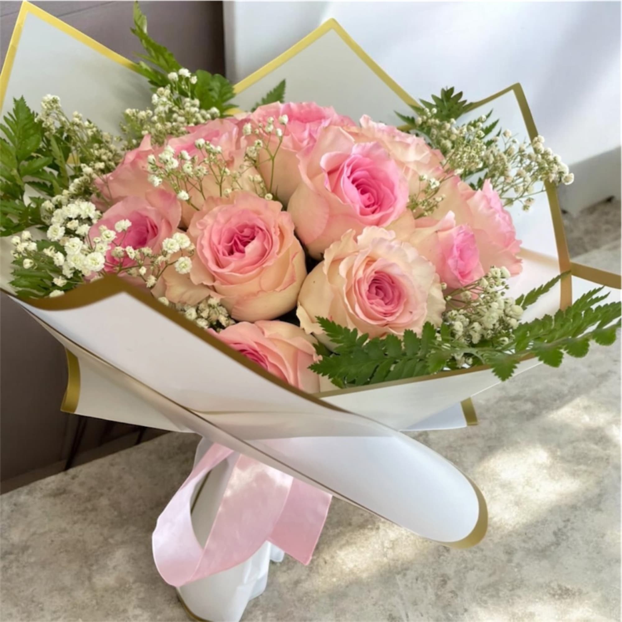 Pink roses wrapped in white paper with a pink ribbon