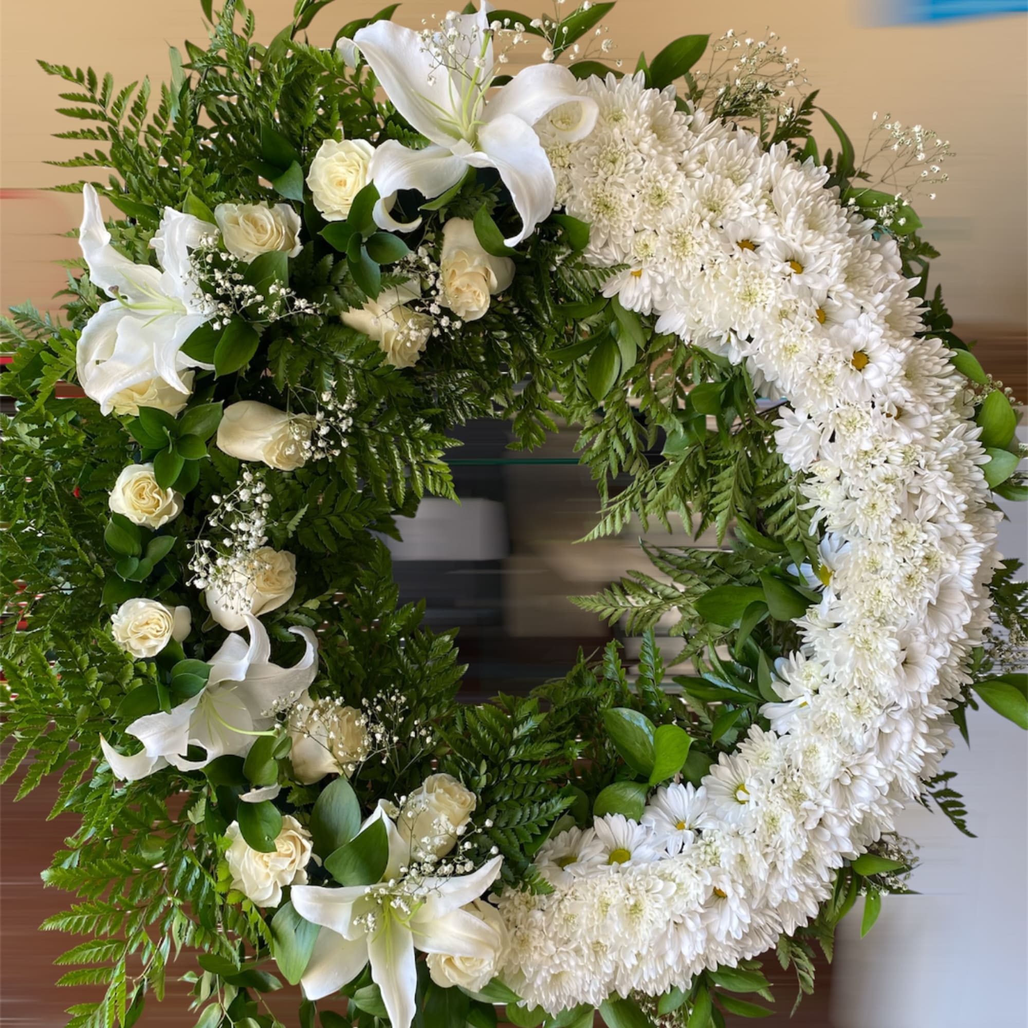 White floral wreath with lilies, roses, and daisies