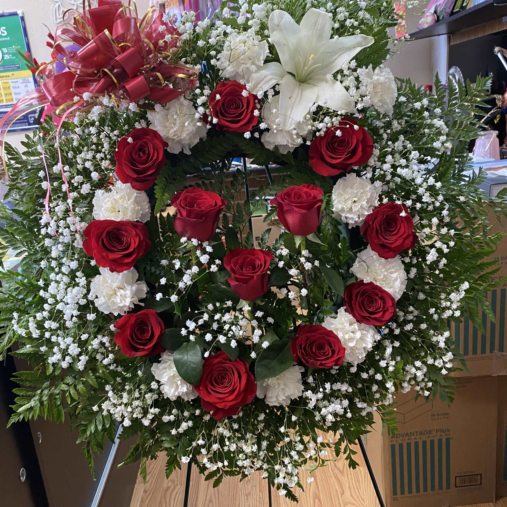 Standing floral wreath with red and white roses and a white lily