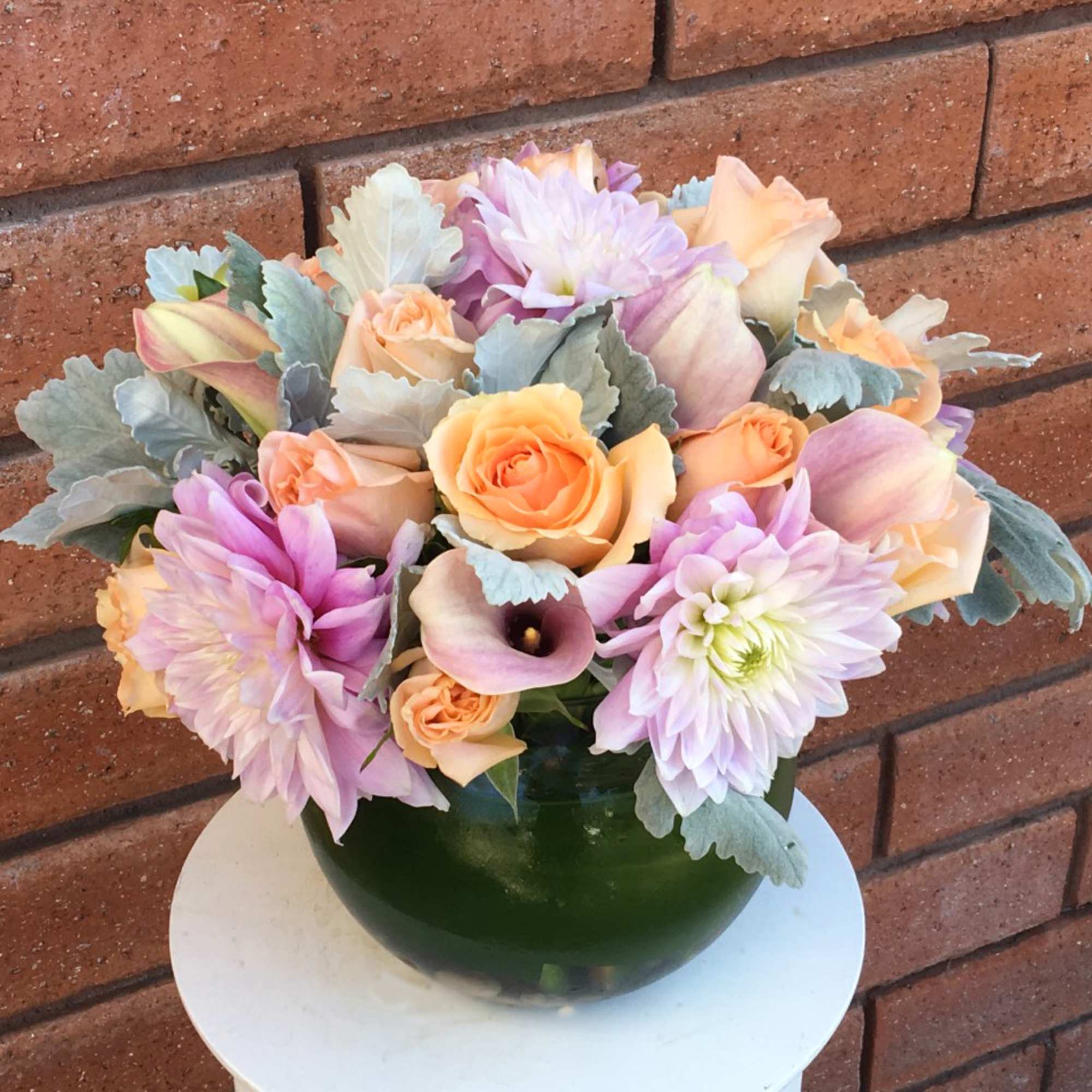 Pastel bouquet of roses, dahlias, and calla lilies in a green vase