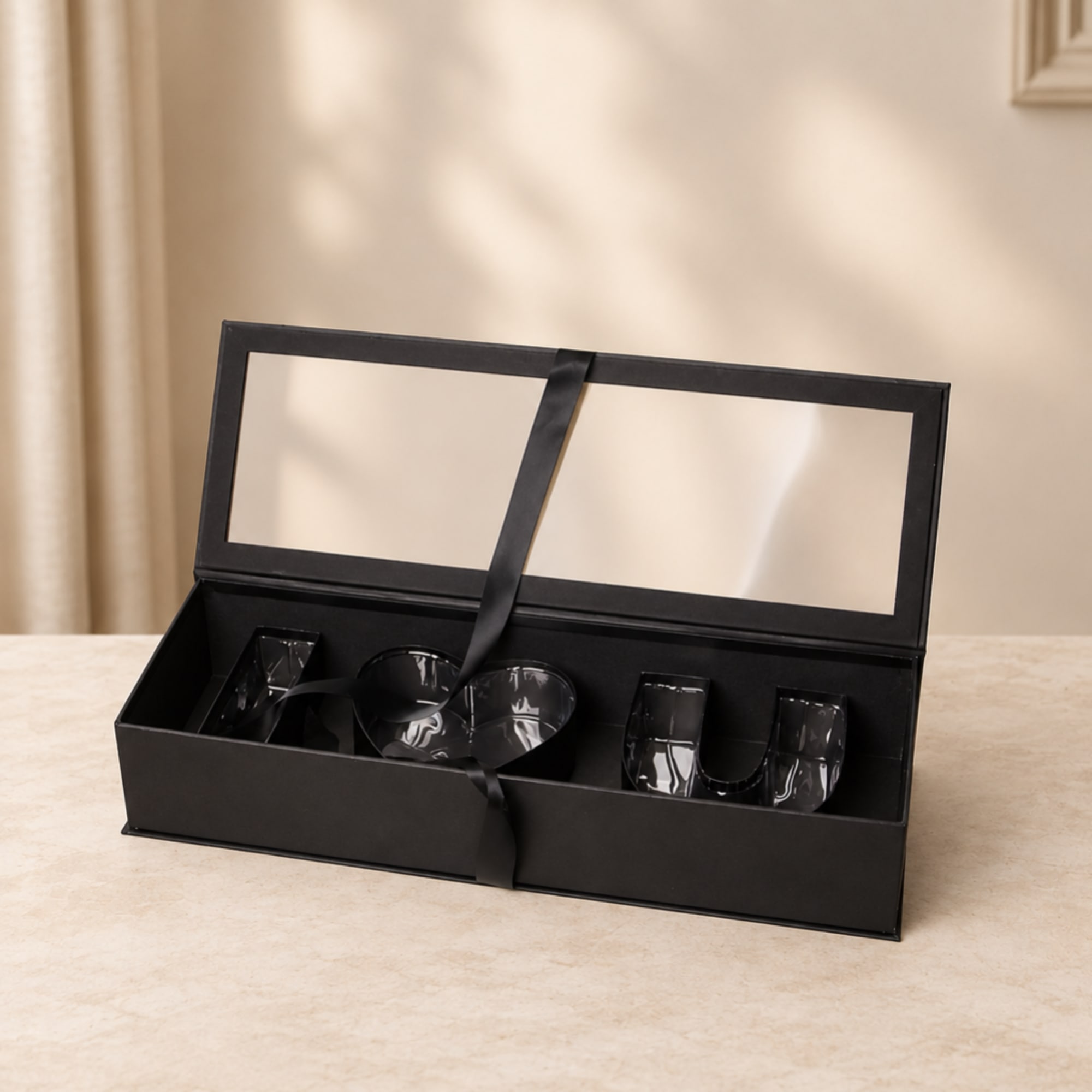 Black gift box with clear letter-shaped inserts and ribbon