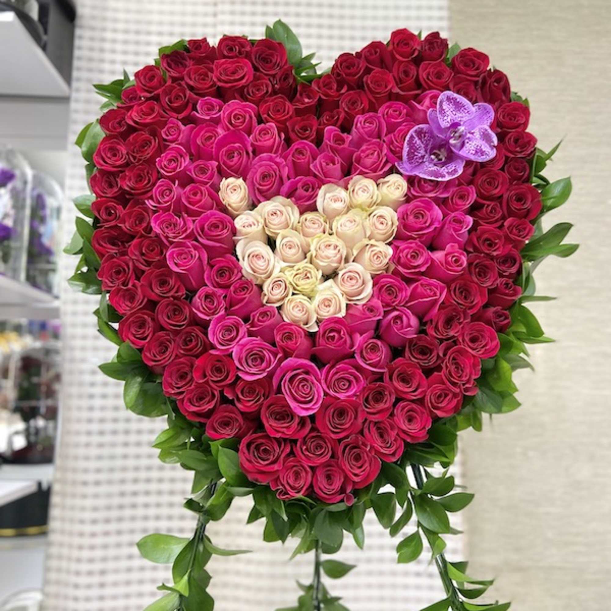Large heart-shaped arrangement of red, pink, and cream roses with a purple orchid accent.