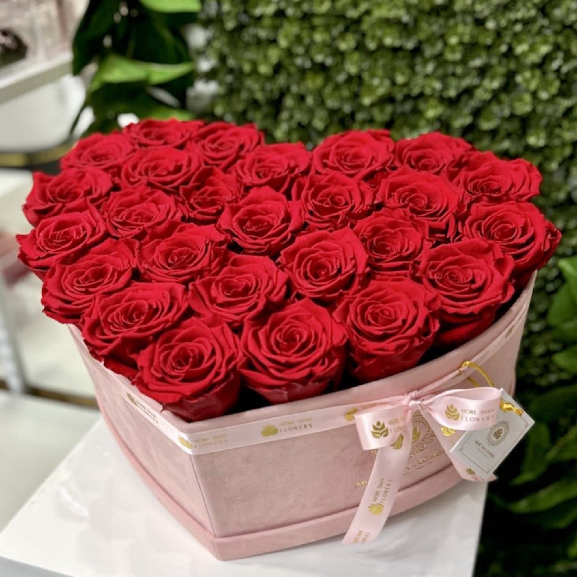 Heart-shaped blush box filled with red roses on a white pedestal