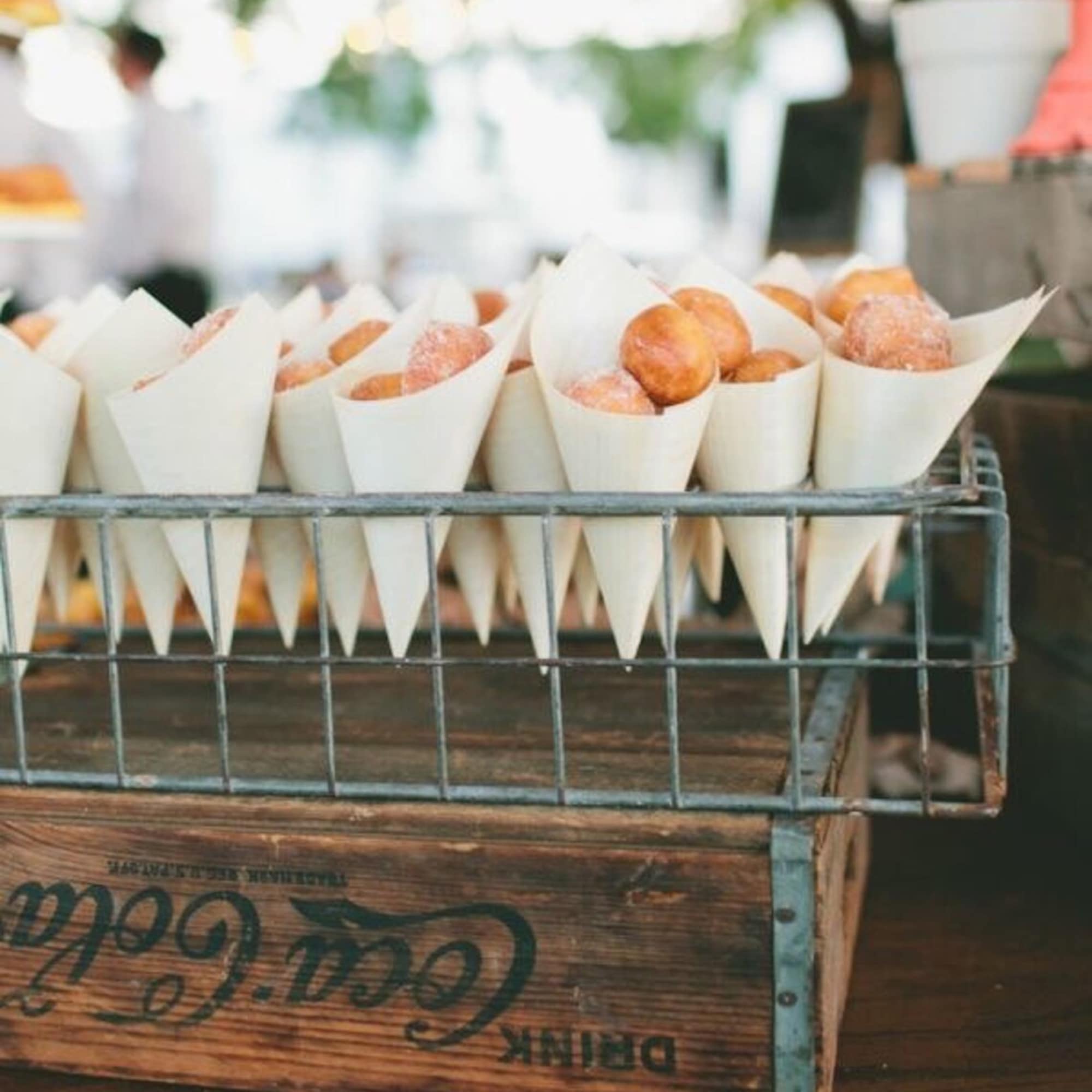 Tray of sugared doughnut holes in paper cones on a wooden crate