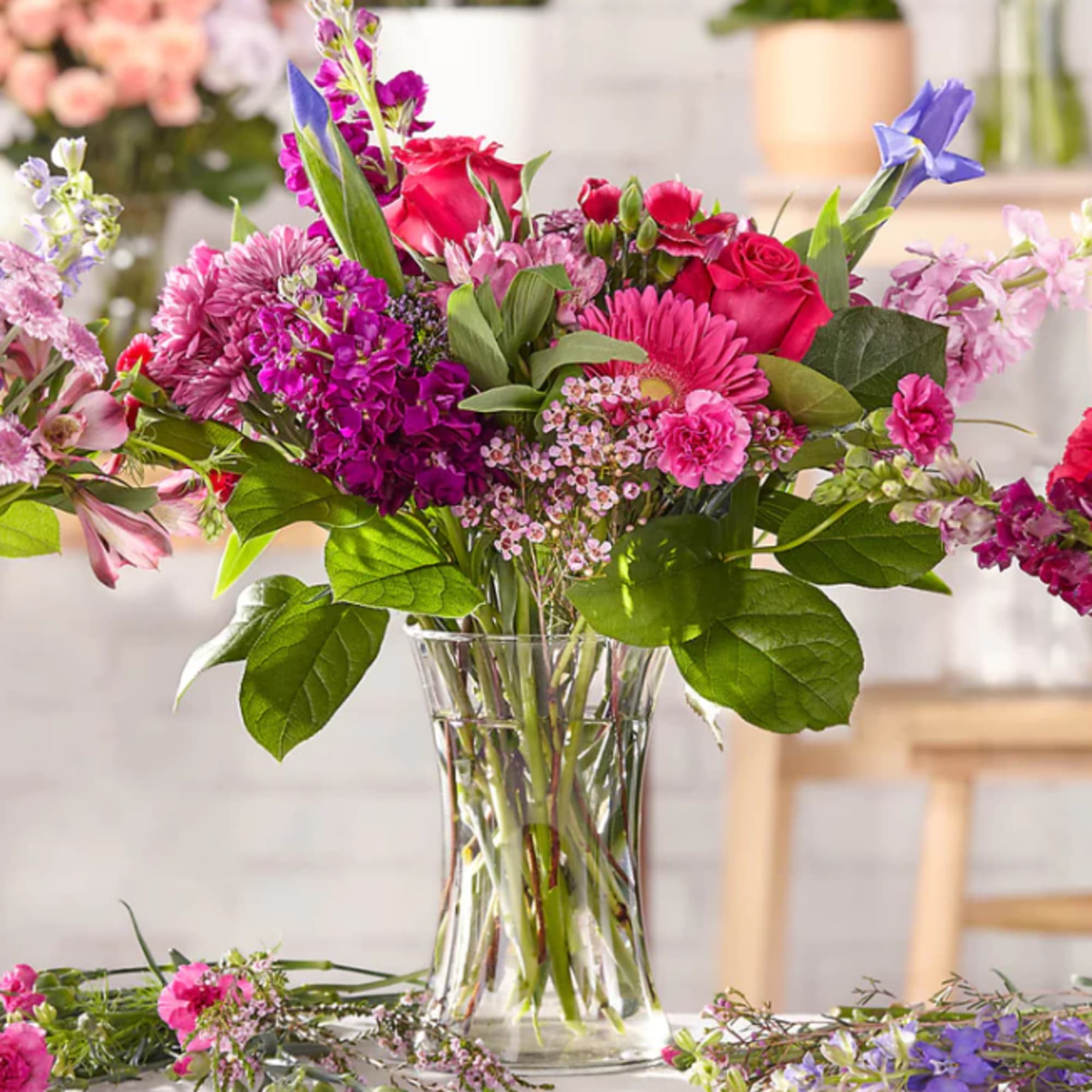 Mixed pink and purple flowers arranged in a clear glass vase