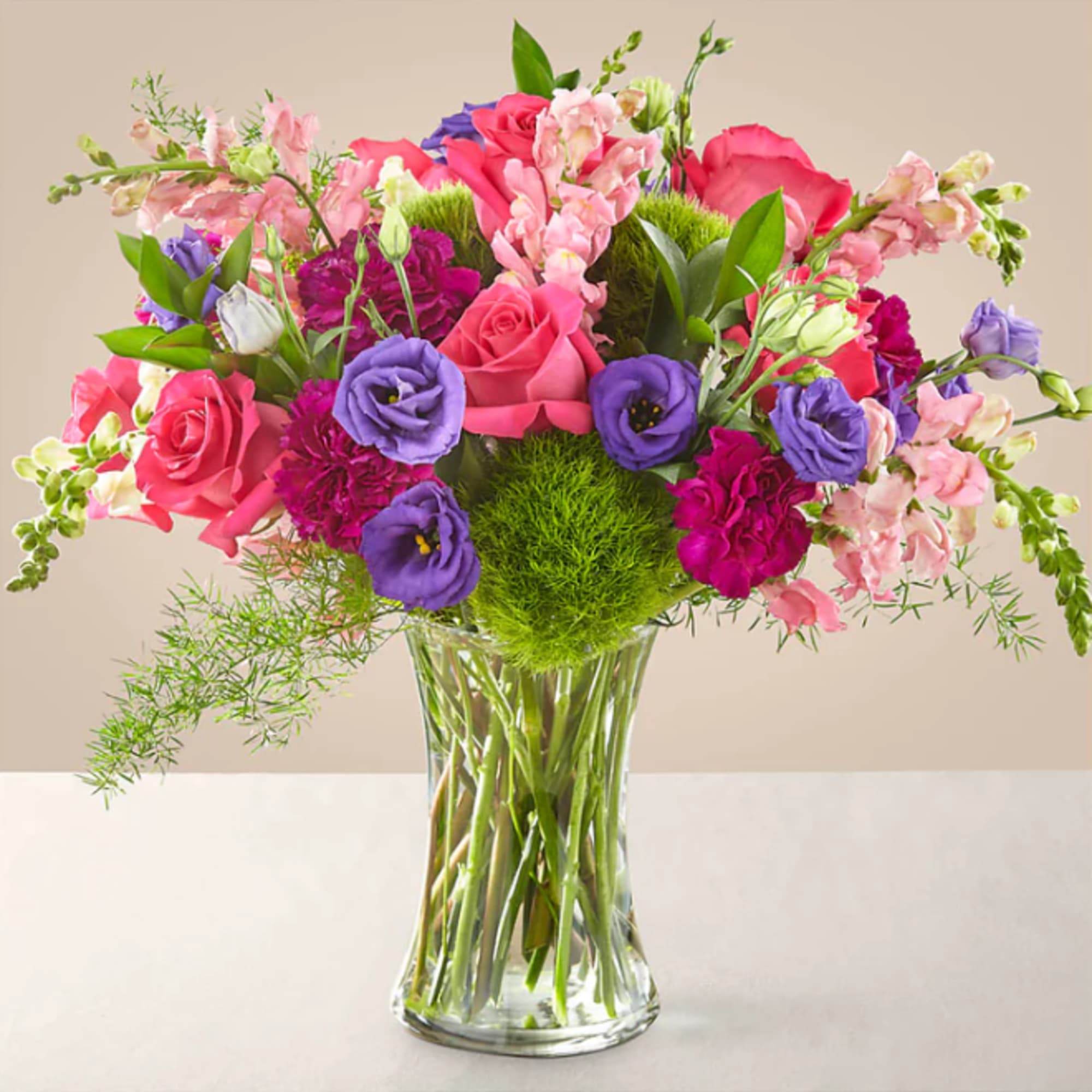 Mixed pink and purple flowers arranged in a clear glass vase