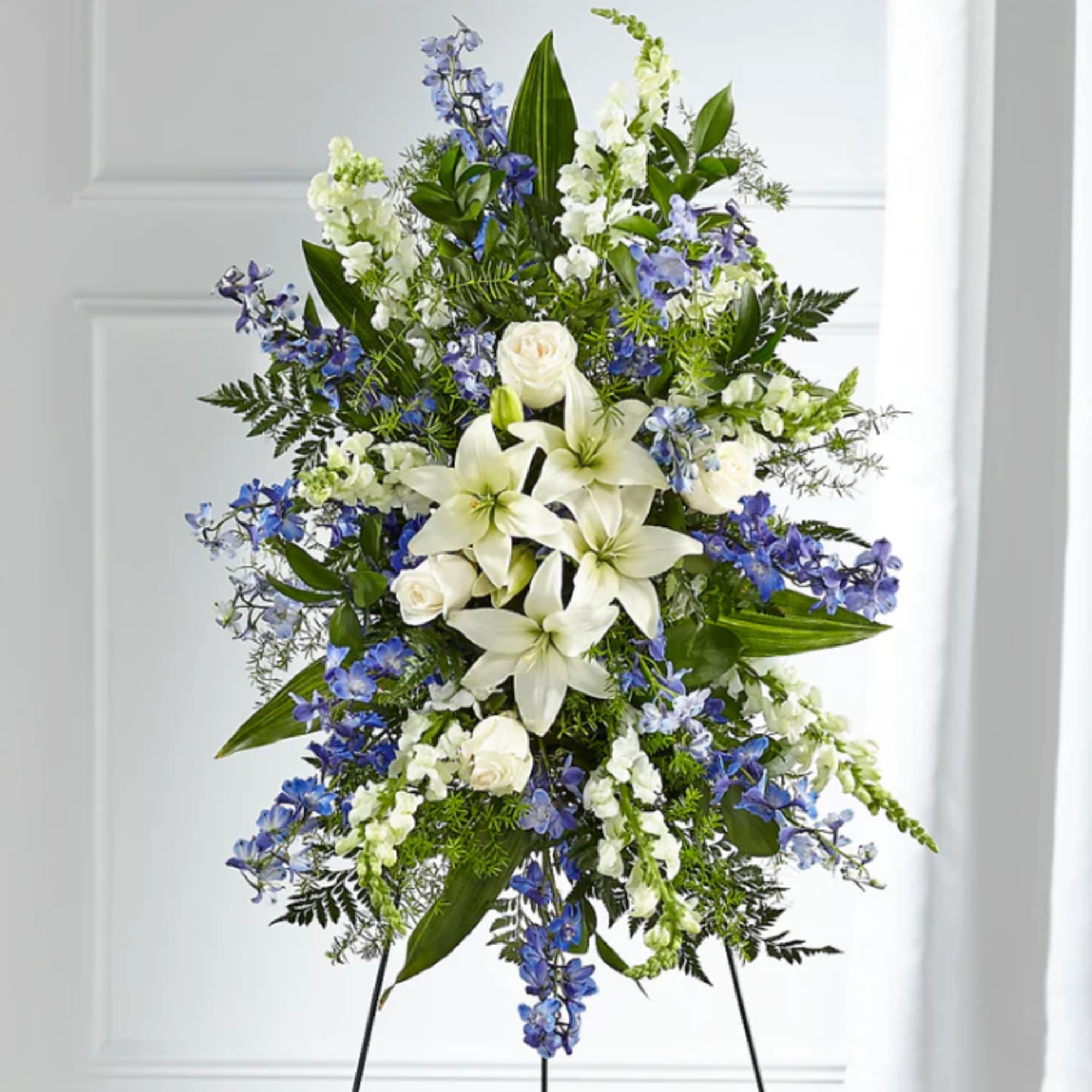 Standing floral spray with white lilies, roses, and blue flowers