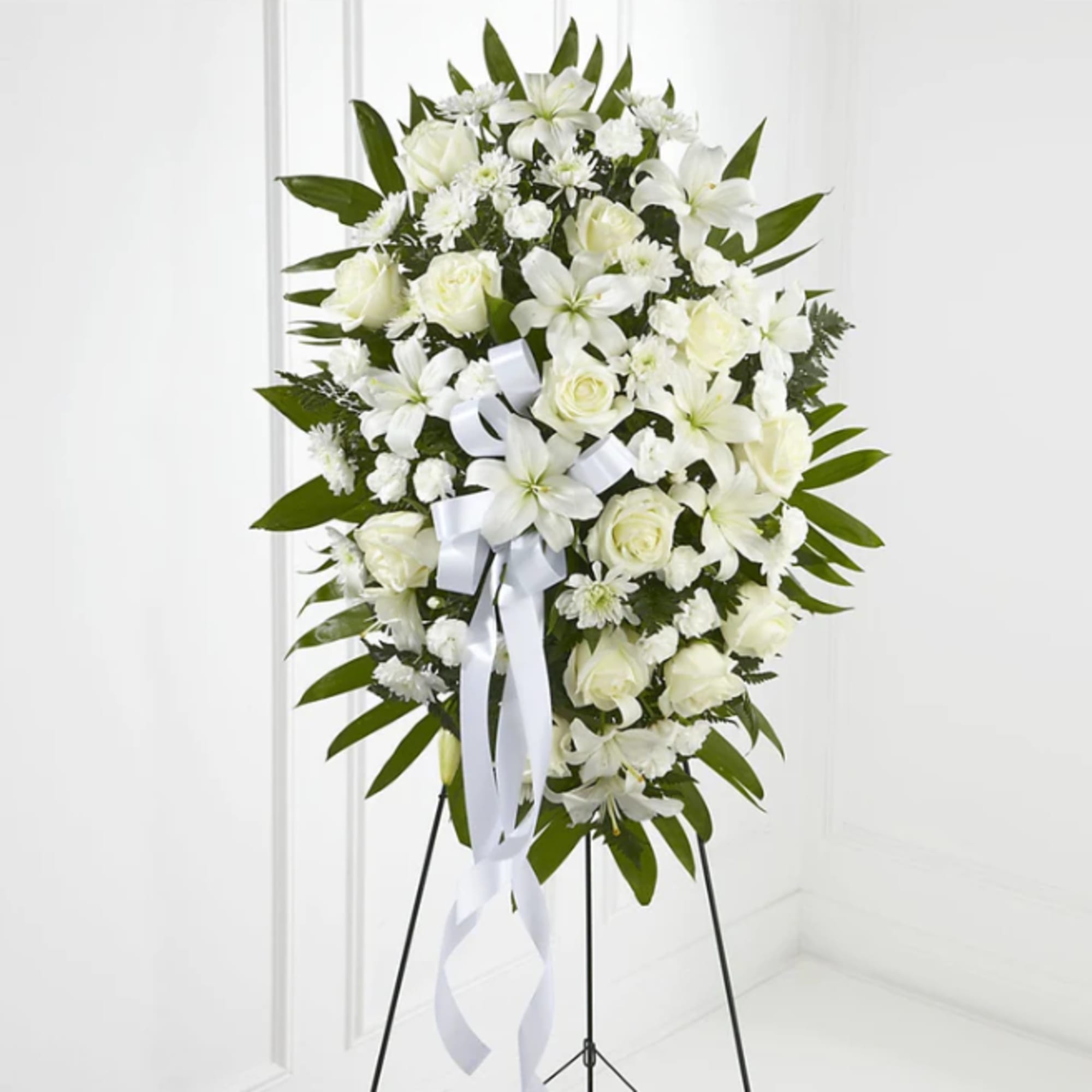White floral standing spray with roses and lilies on an easel