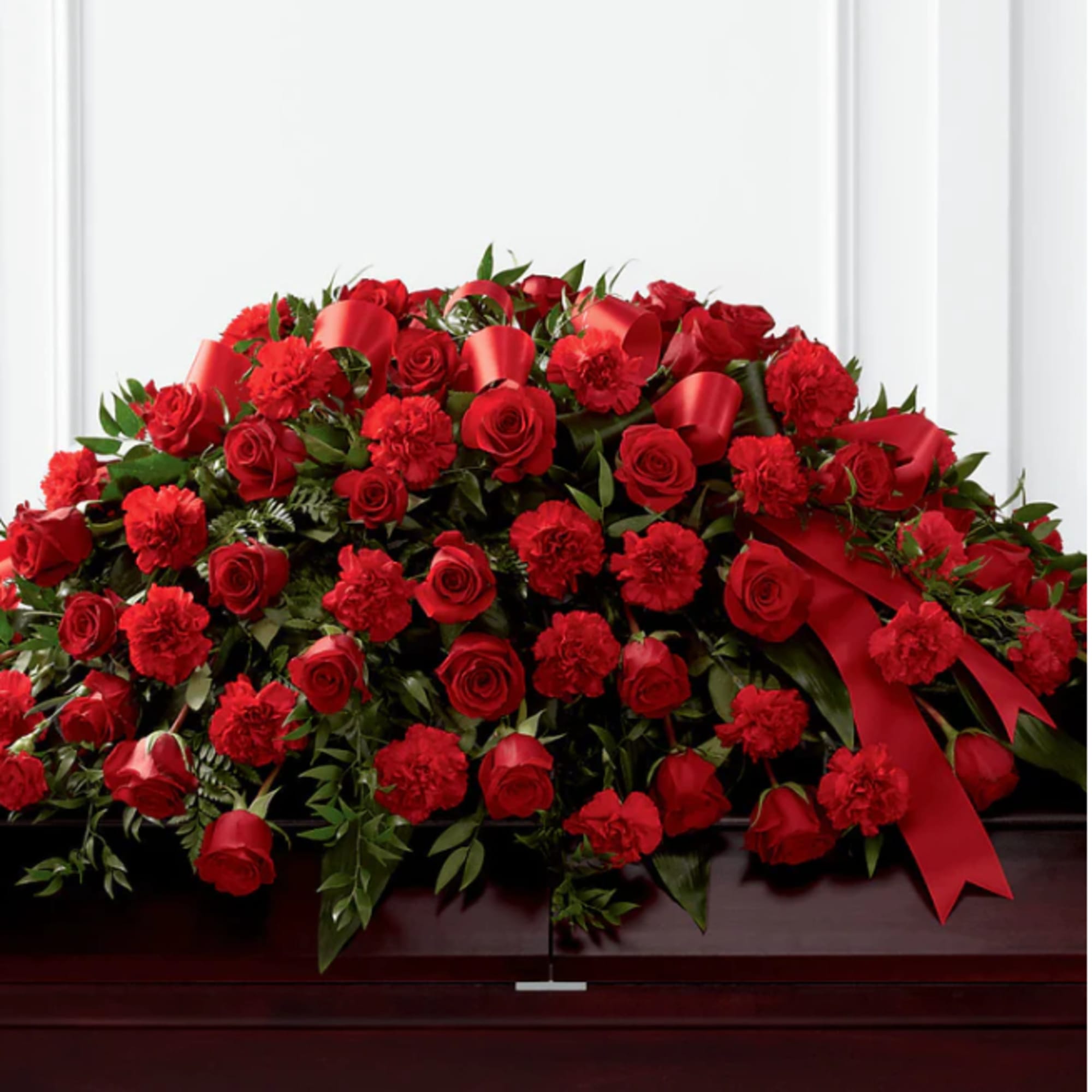 Large red rose and carnation casket spray with ribbon accents