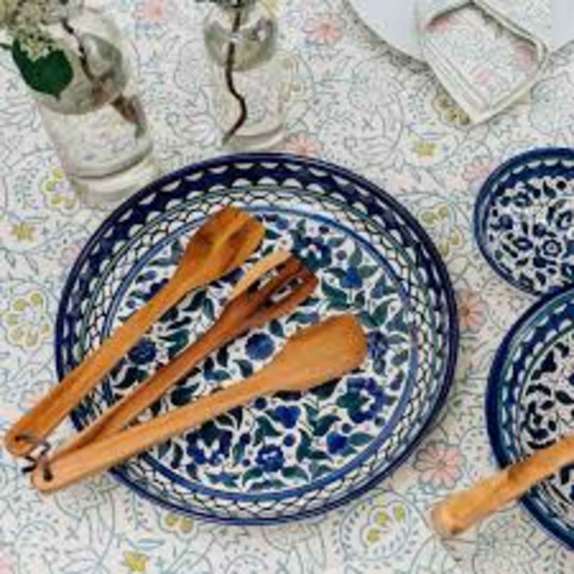 Blue patterned plates with wooden utensils on a floral tablecloth