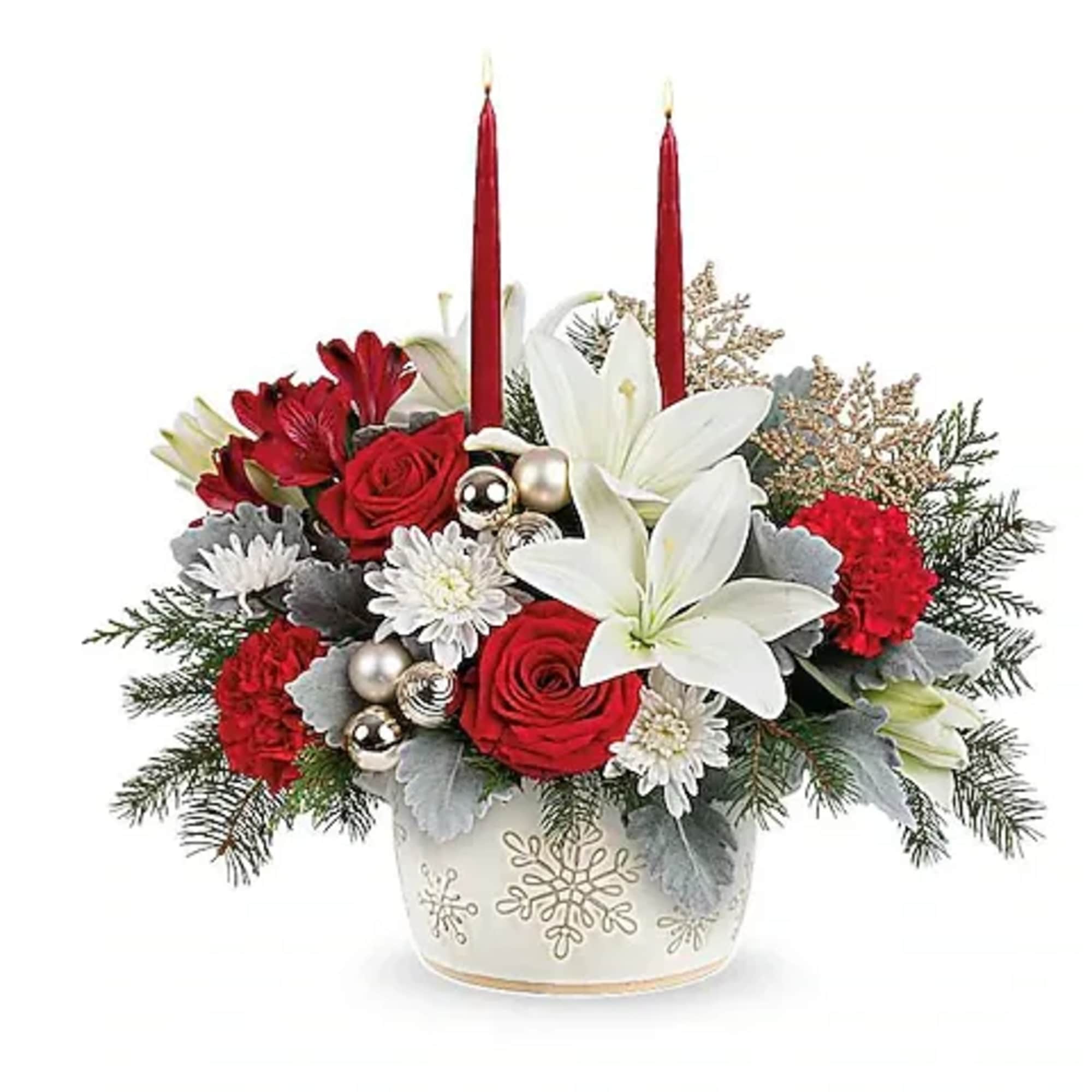 Holiday arrangement with red roses, white lilies, and two red candles in a snowflake vase