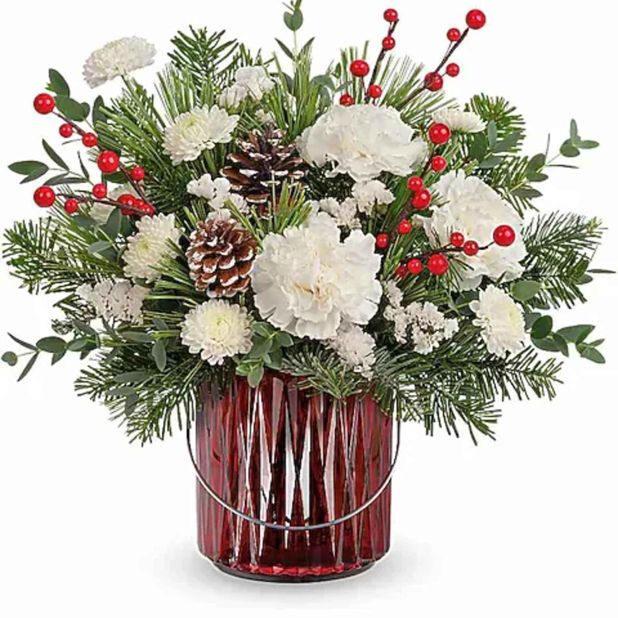 White flowers and pine arranged in a red glass vase with red berry accents