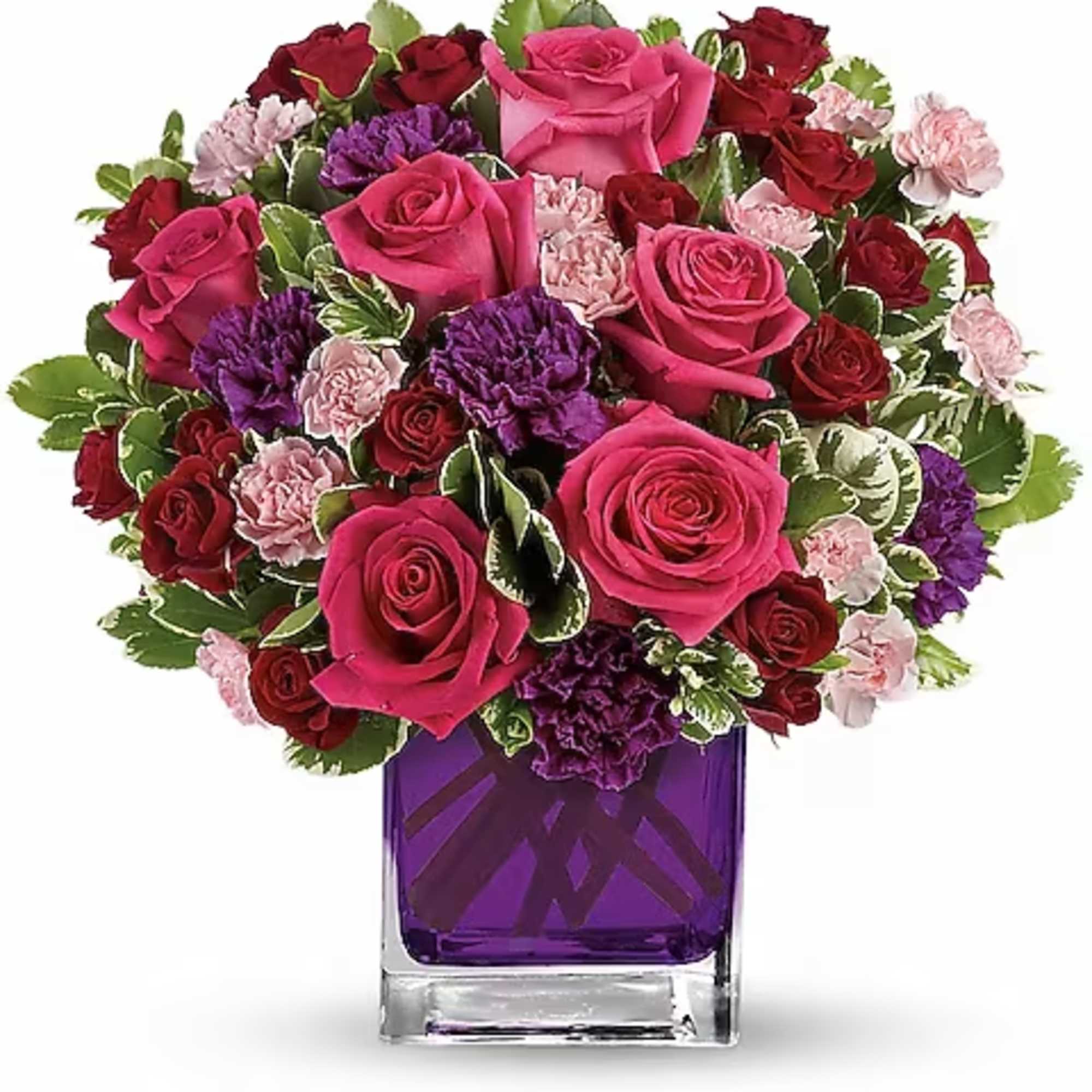 Bouquet of pink and red roses with purple carnations in a purple glass vase