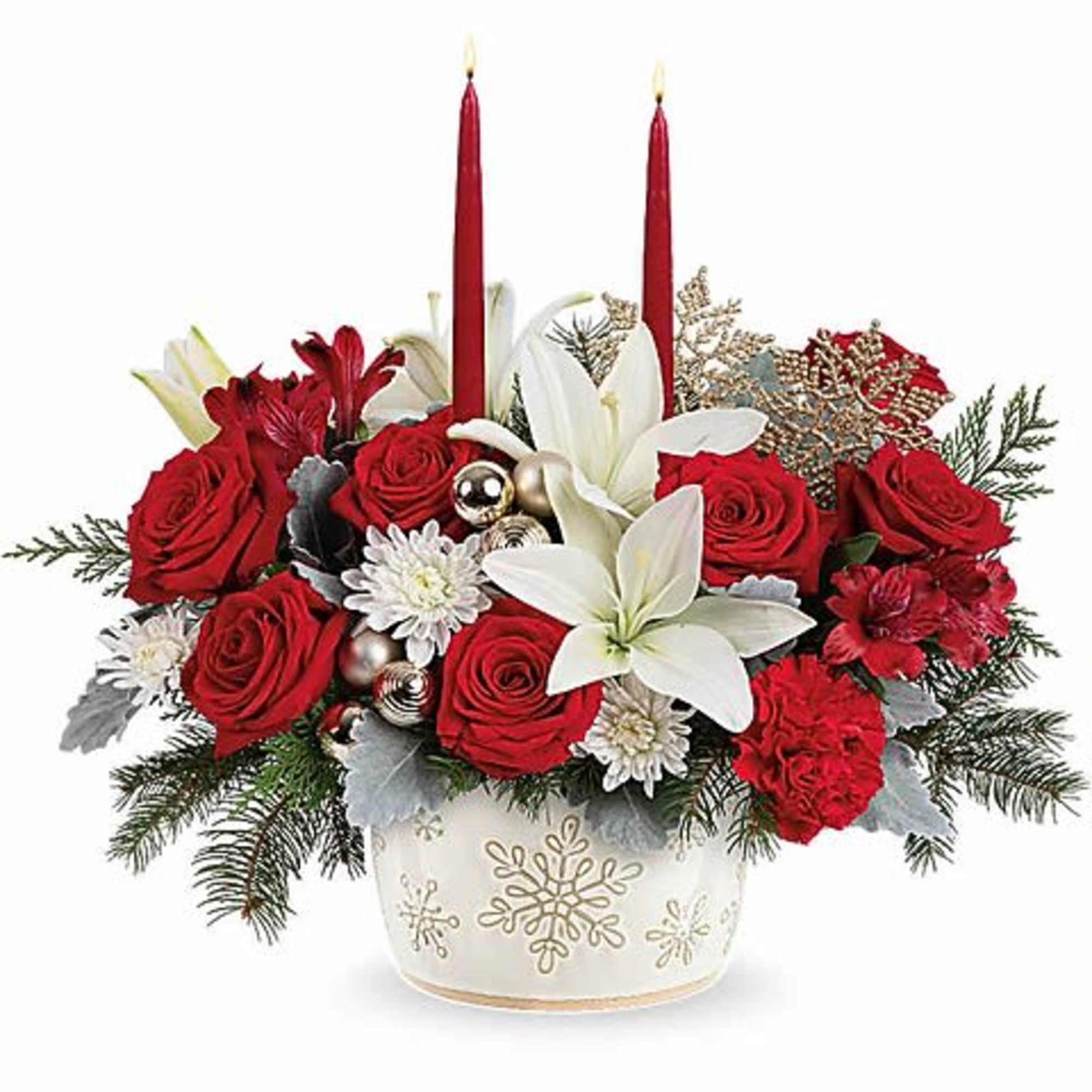 Red and white floral arrangement in a snowflake vase with two red candles