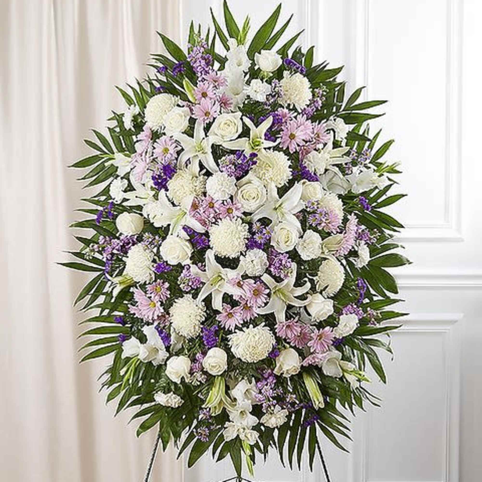 Standing funeral spray of white and lavender flowers on an easel